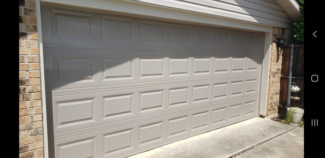 A white garage door is sitting on the side of a house.
