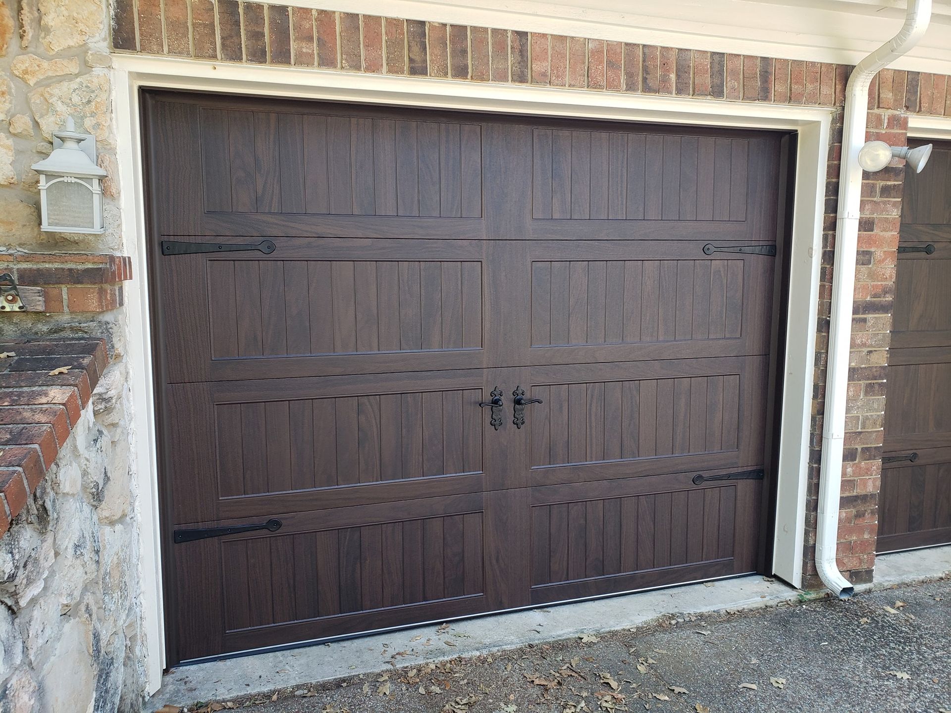 A brown garage door is sitting in front of a brick building.