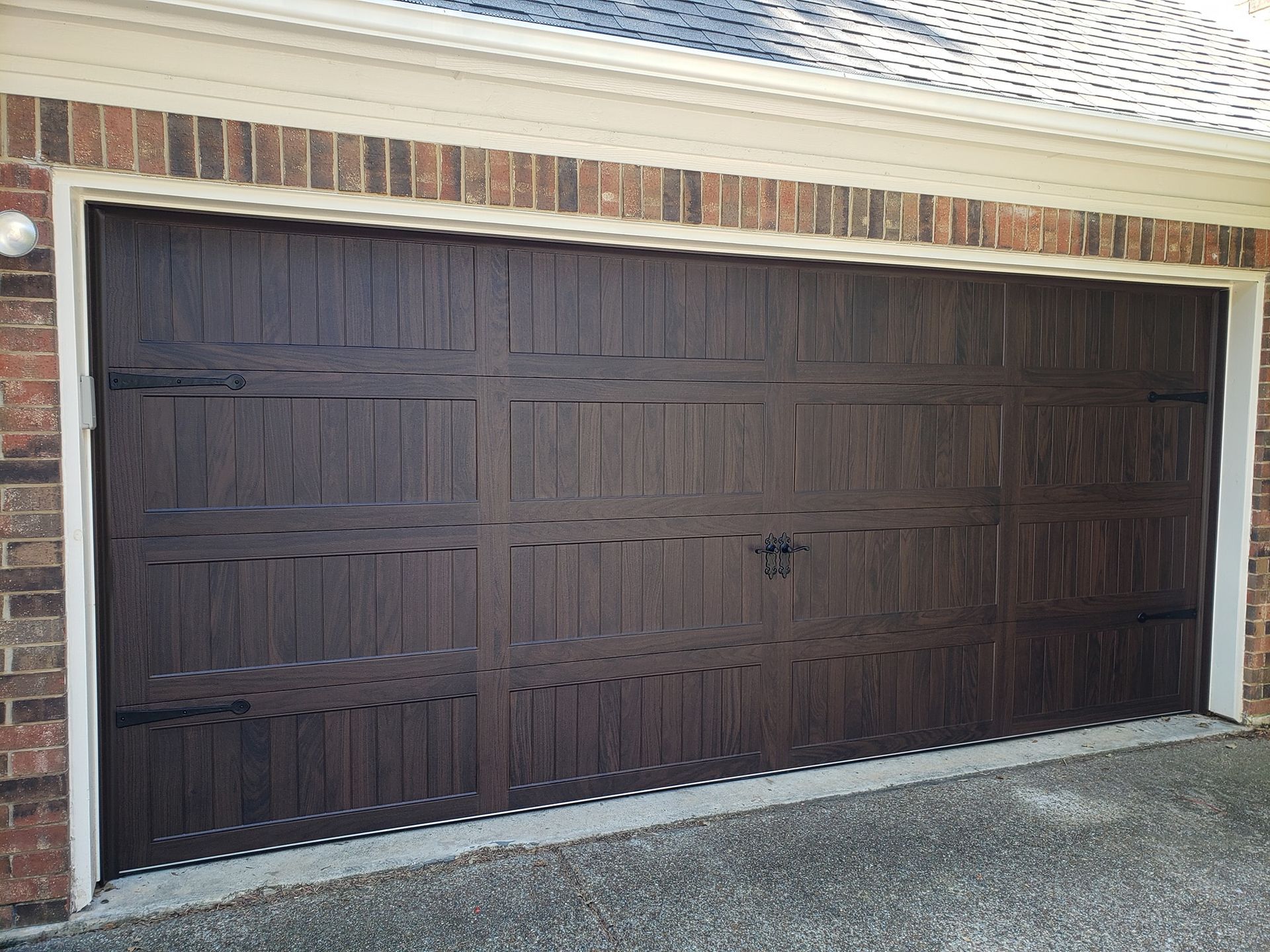 A brown garage door is sitting in front of a brick building.