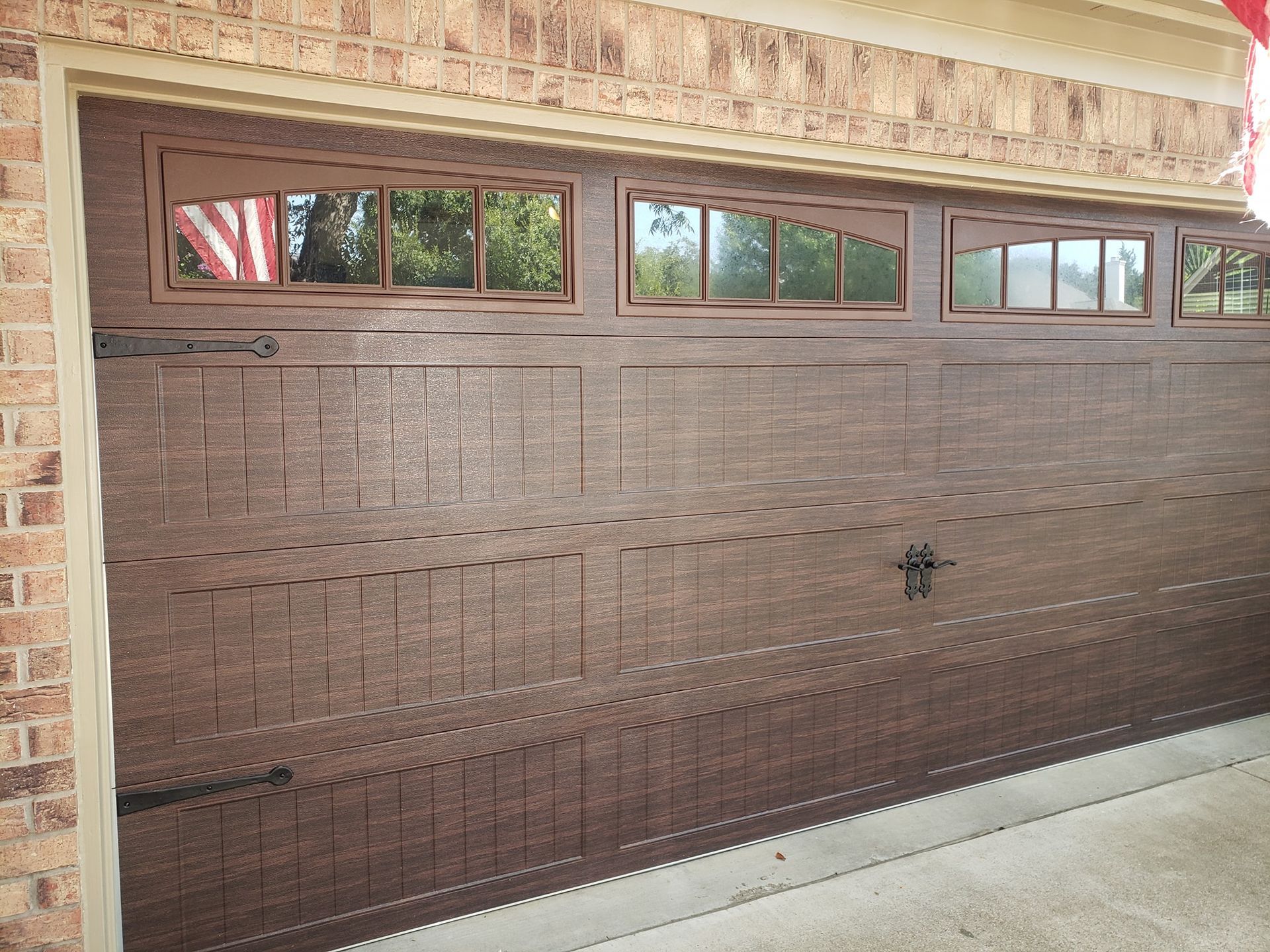 A brown garage door with a brick building in the background.
