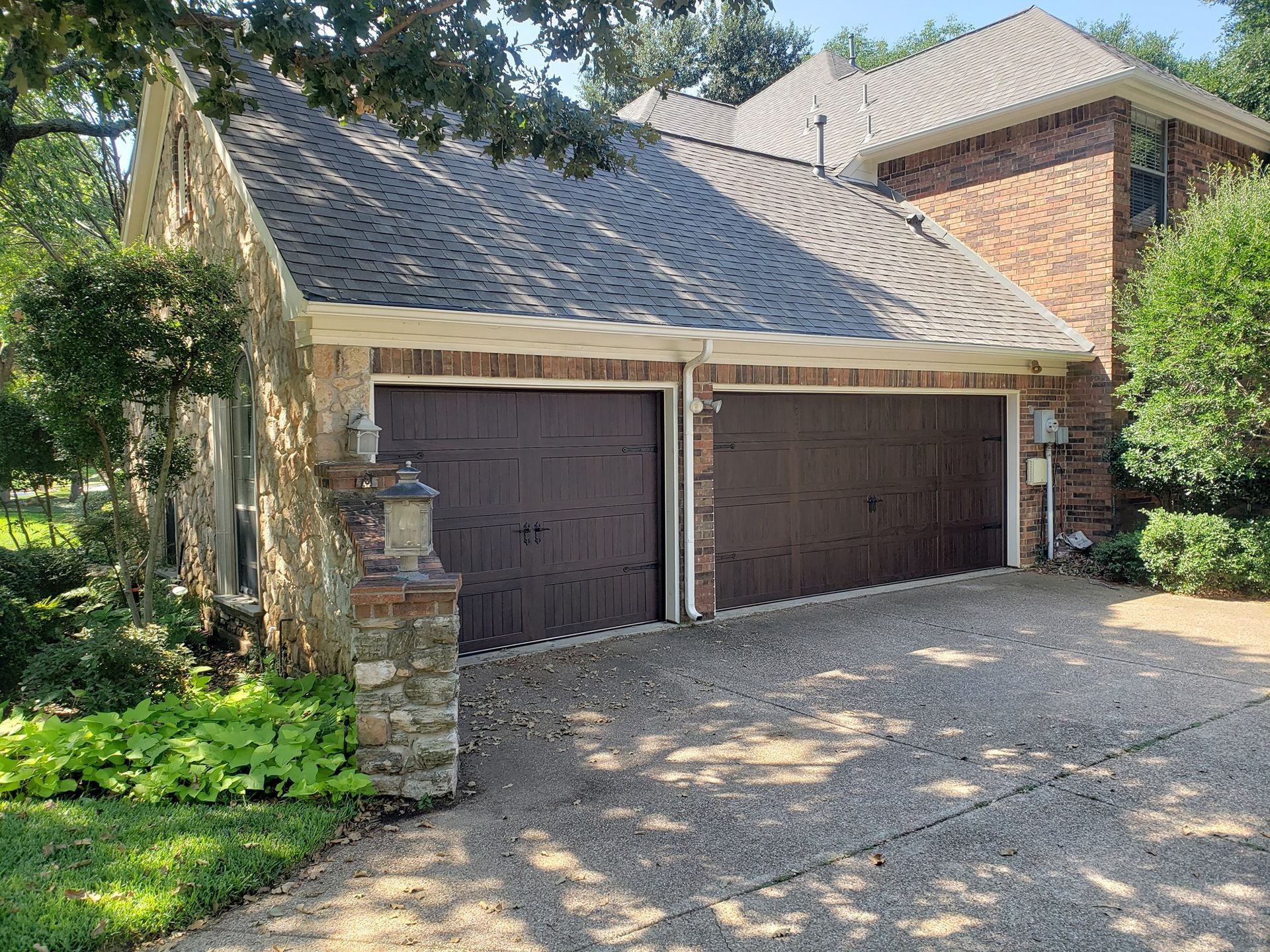 A large brick house with two garage doors and a driveway.