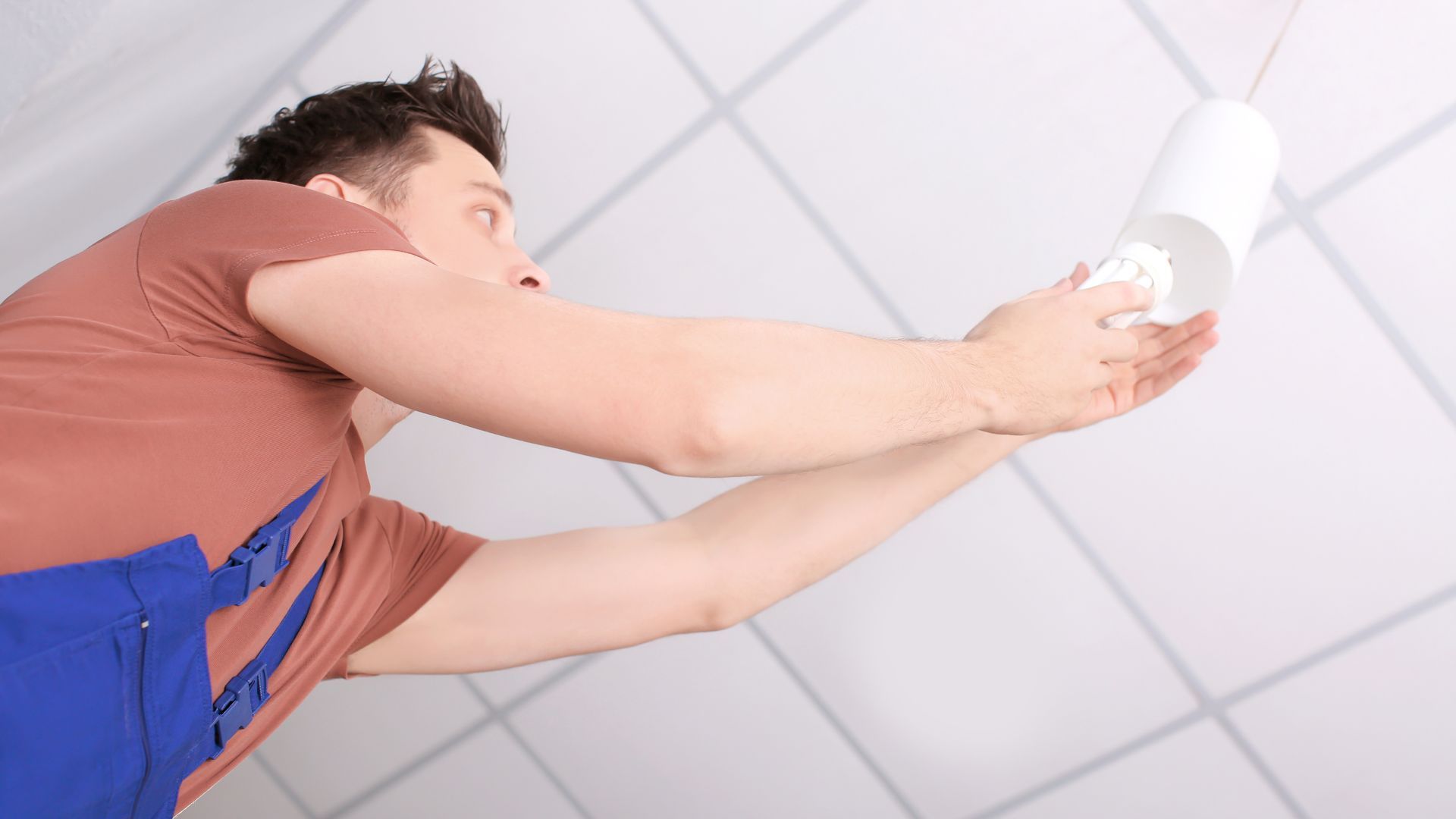 A man is hanging a light bulb from the ceiling.
