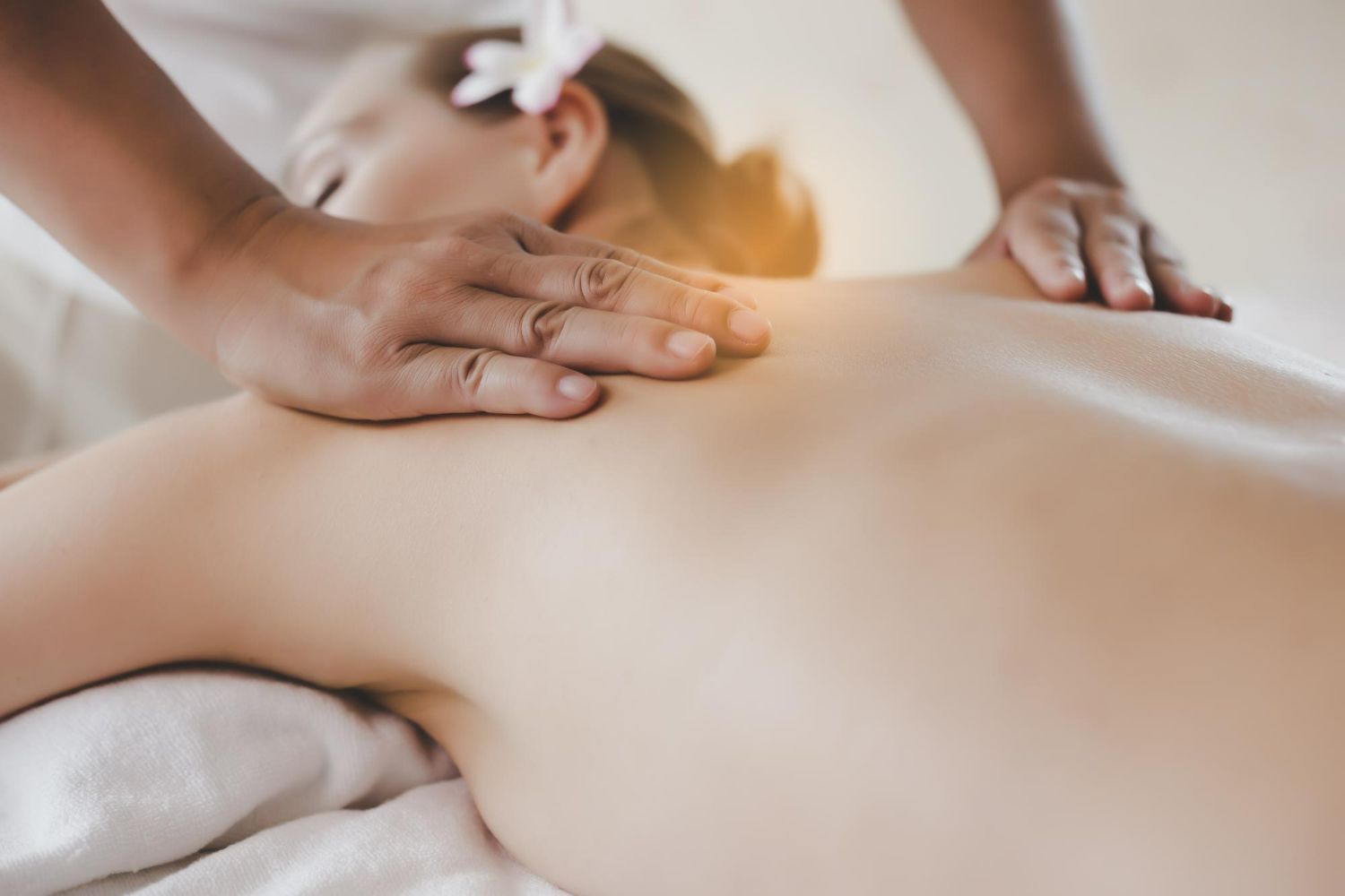 Hands massaging a person's bare back in a spa setting.
