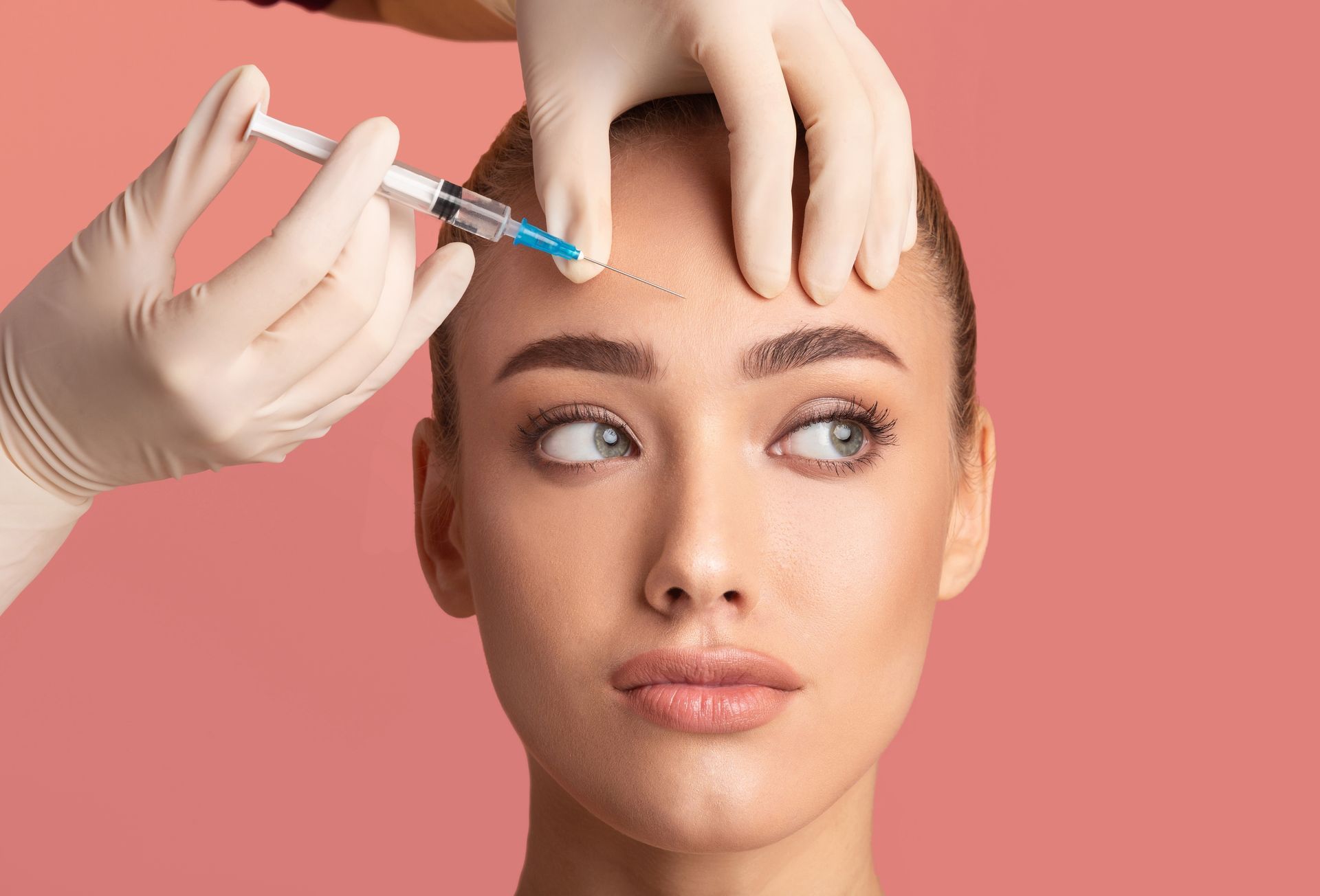 A woman is getting a botox injection in her forehead.