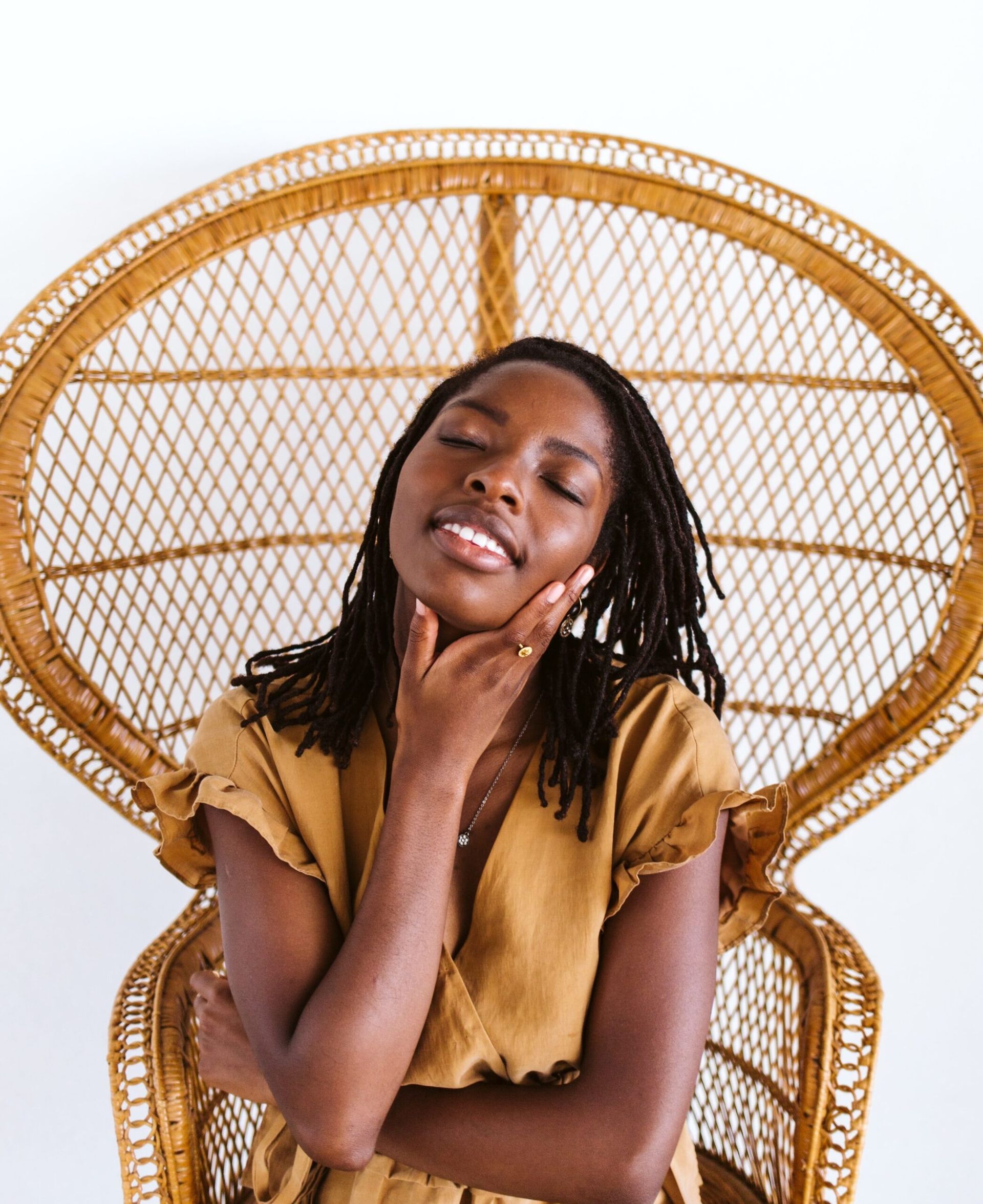 A woman is sitting in a wicker chair with her eyes closed.
