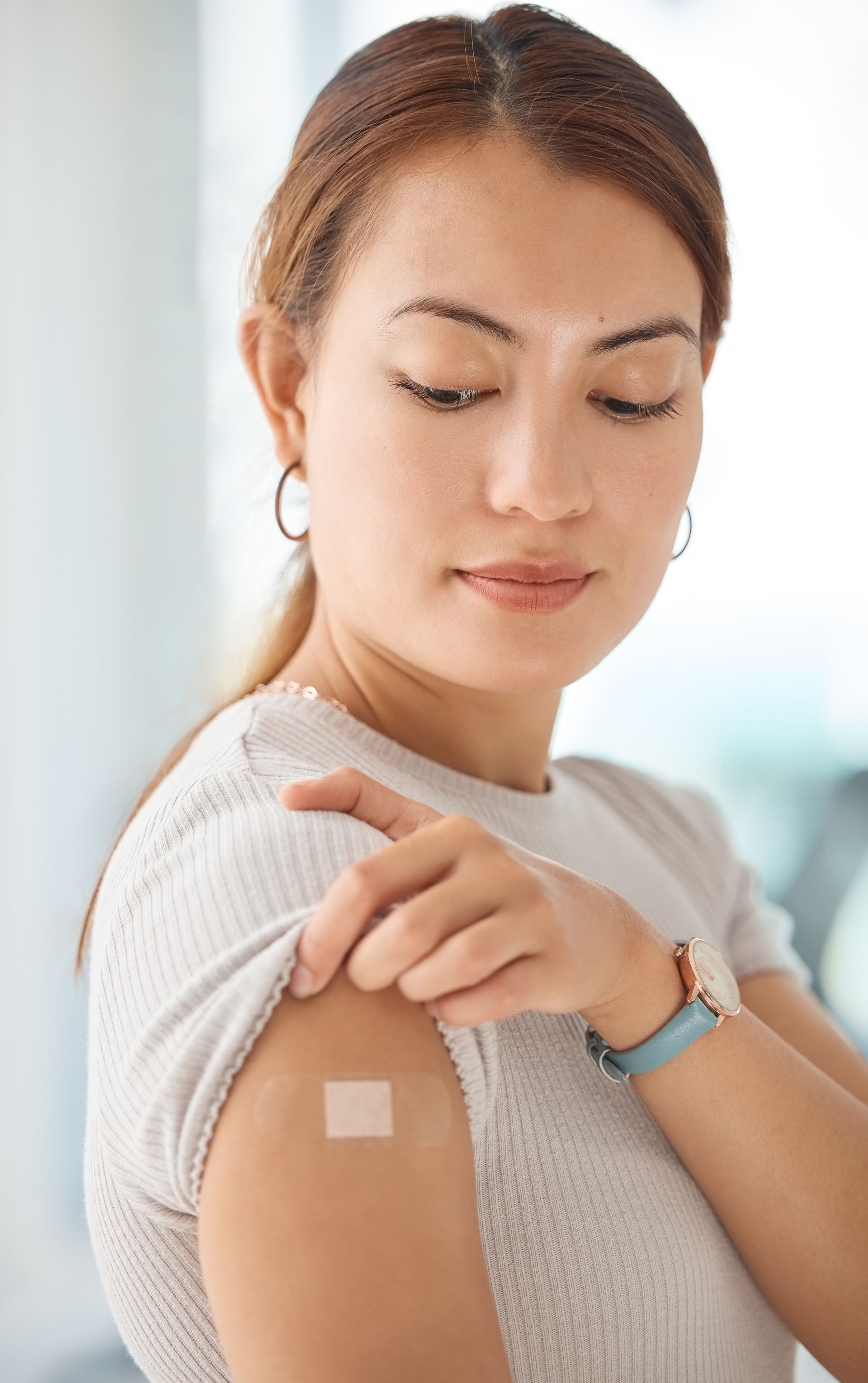 A woman has a bandage on her arm after getting a vaccine.