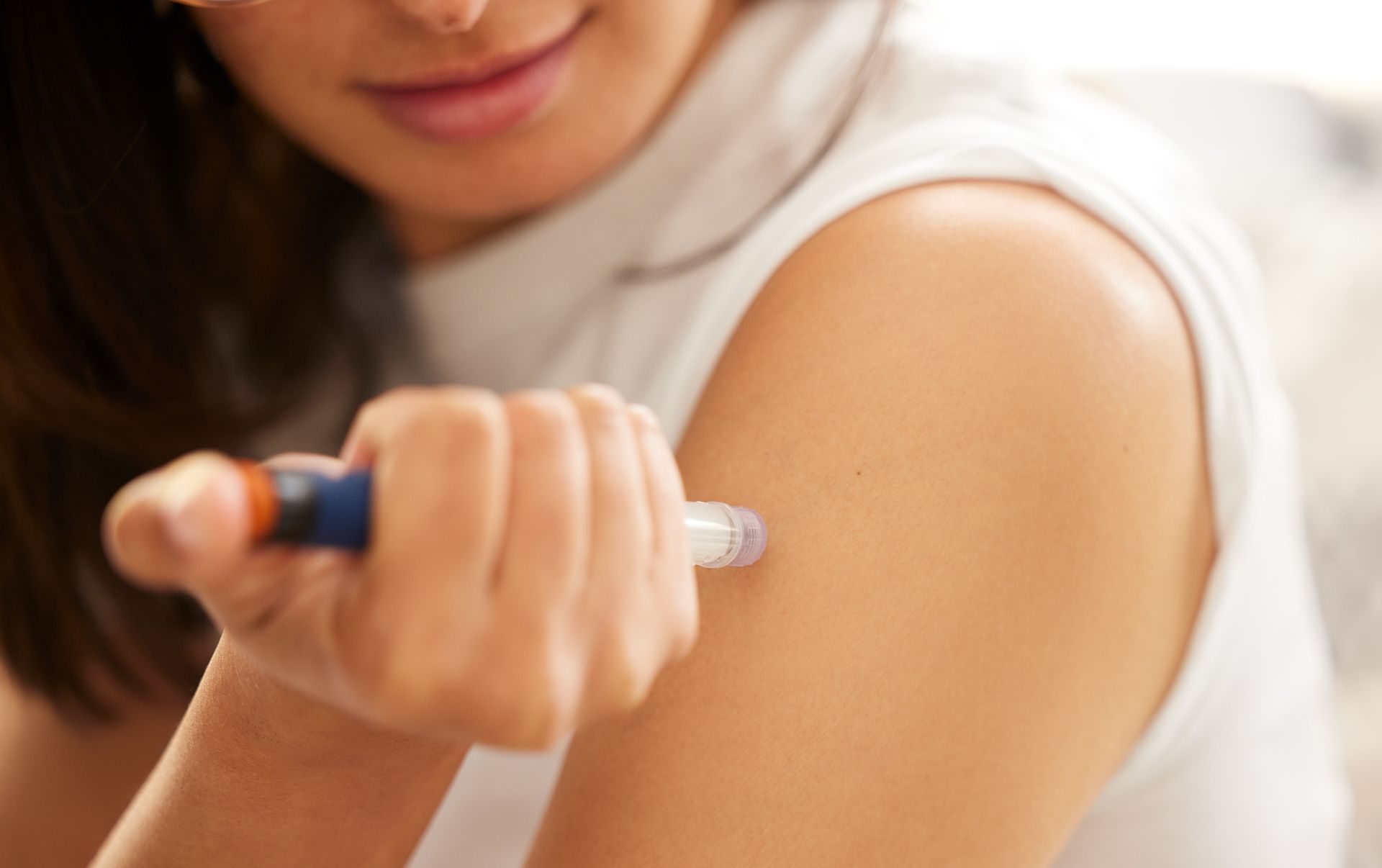 A woman is injecting her arm with an insulin pen