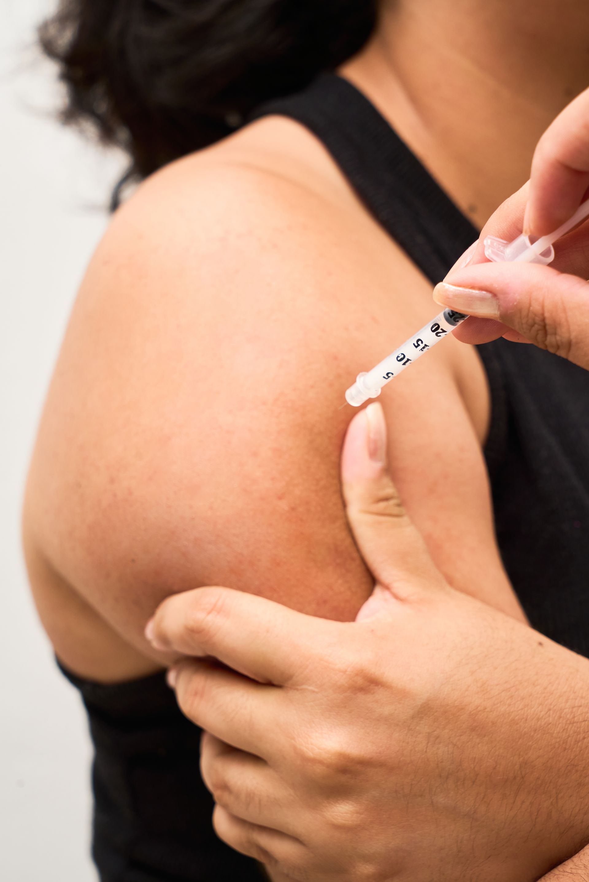 A woman is getting an injection in her arm with a syringe.