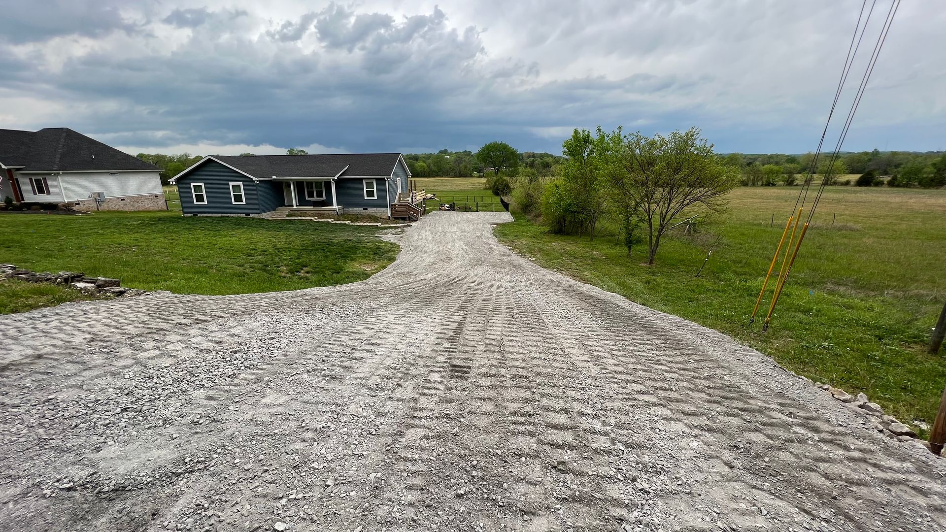 A gravel road leading to a house in the middle of a field.