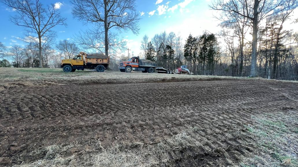 A yellow dump truck is driving down a dirt road.