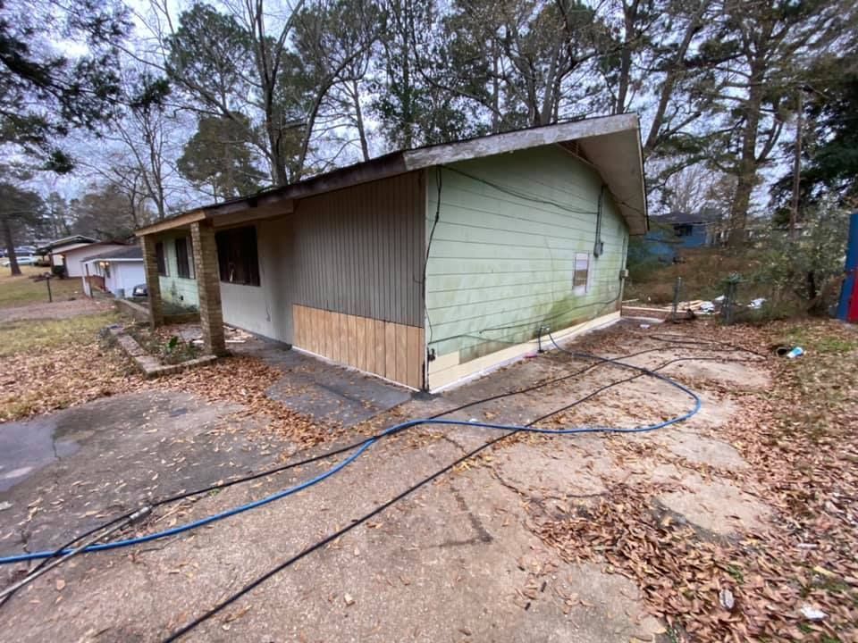 A green house with a hose in front of it.