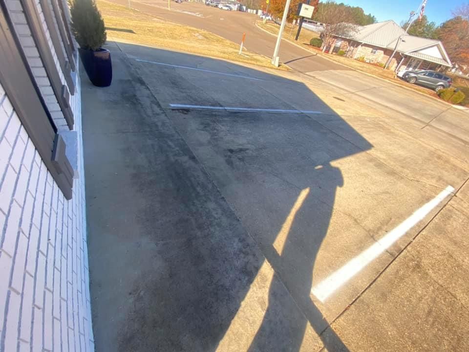 A shadow of a person is cast on the sidewalk in front of a building.