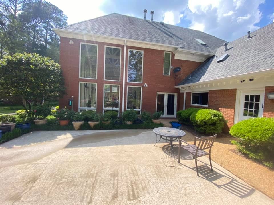 A large brick house with a patio area with a table and chairs in front of it.