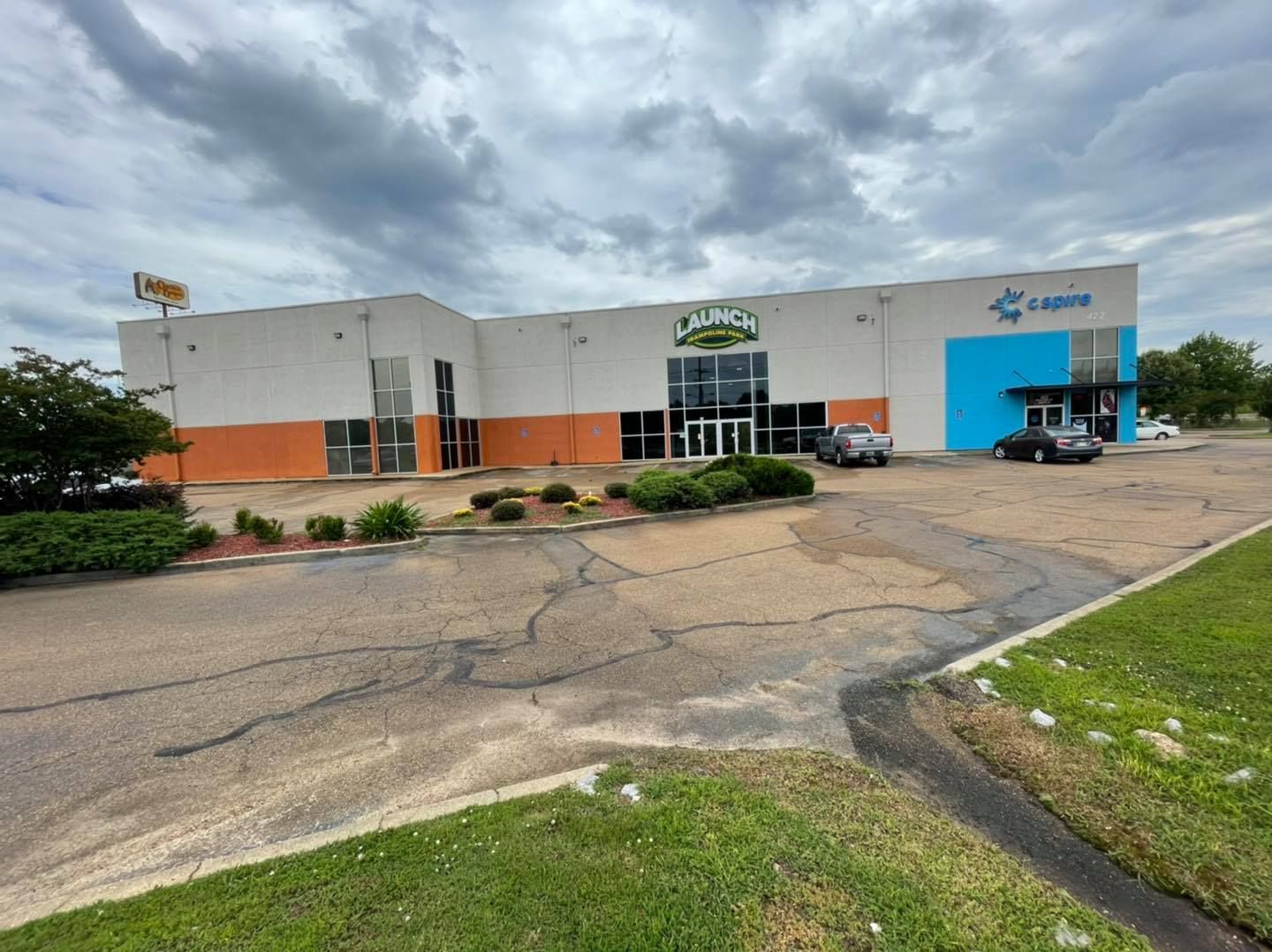 A large building with a lot of windows is sitting on top of a lush green field.