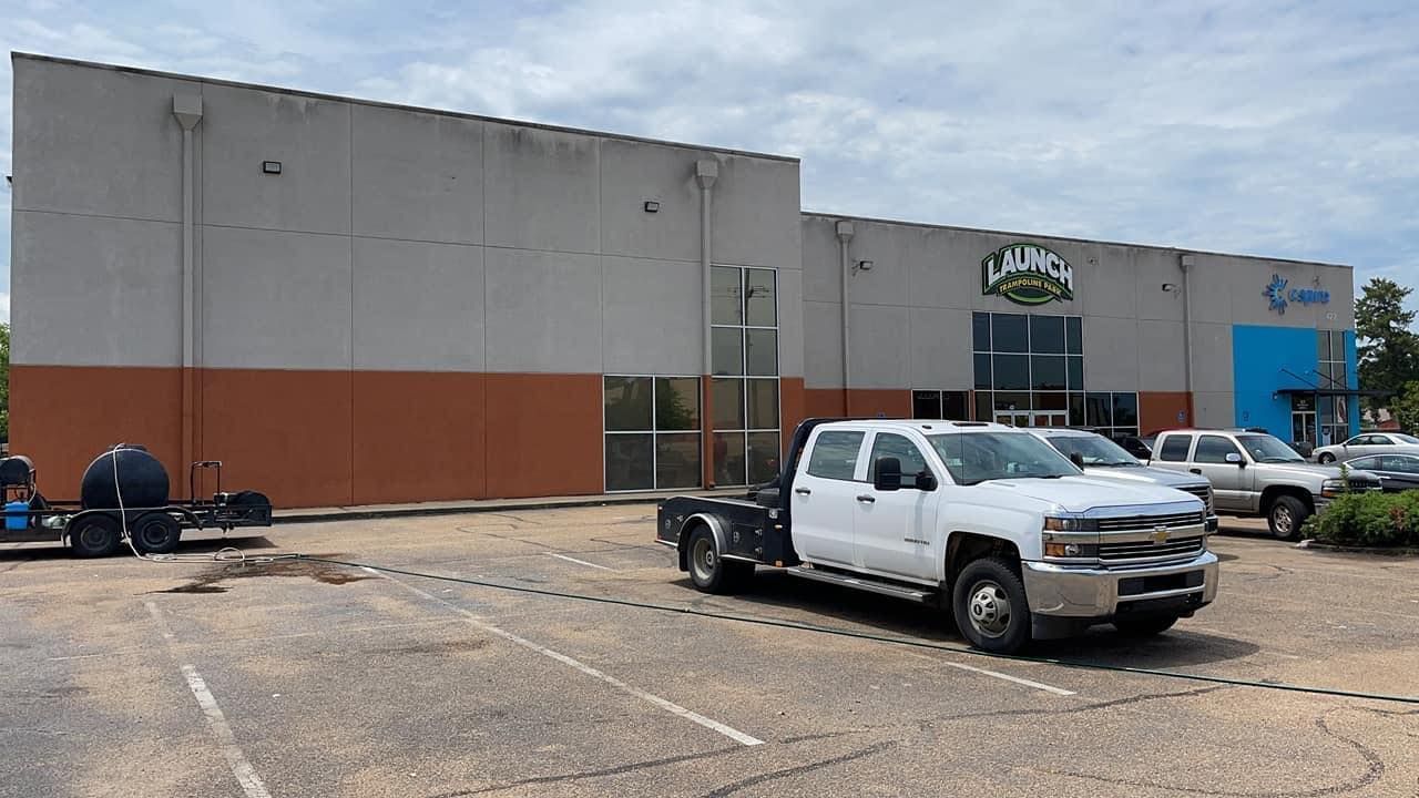 A white truck is parked in front of a large building.