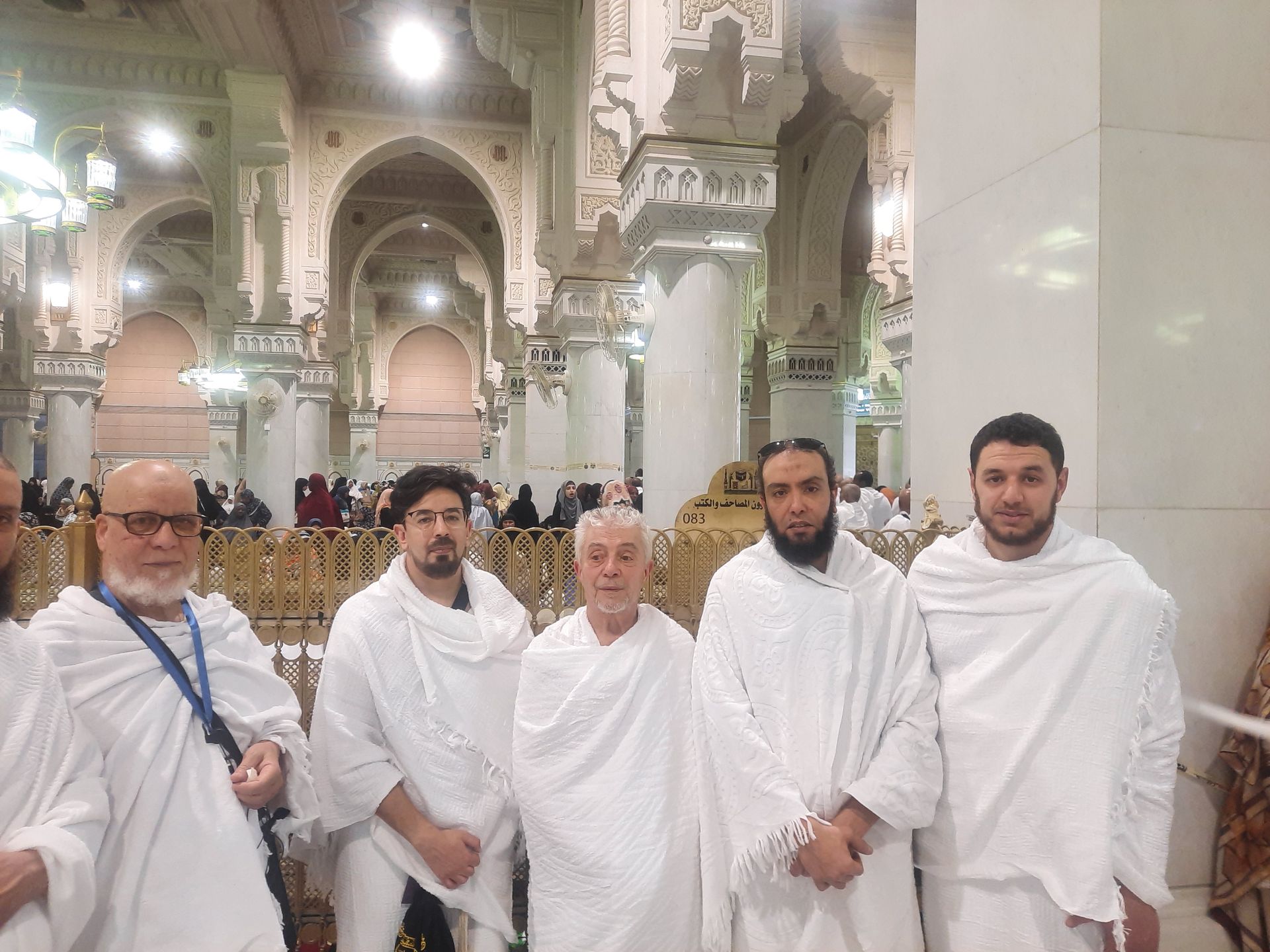 Een groep mannen in witte gewaden poseert voor een foto in een moskee.