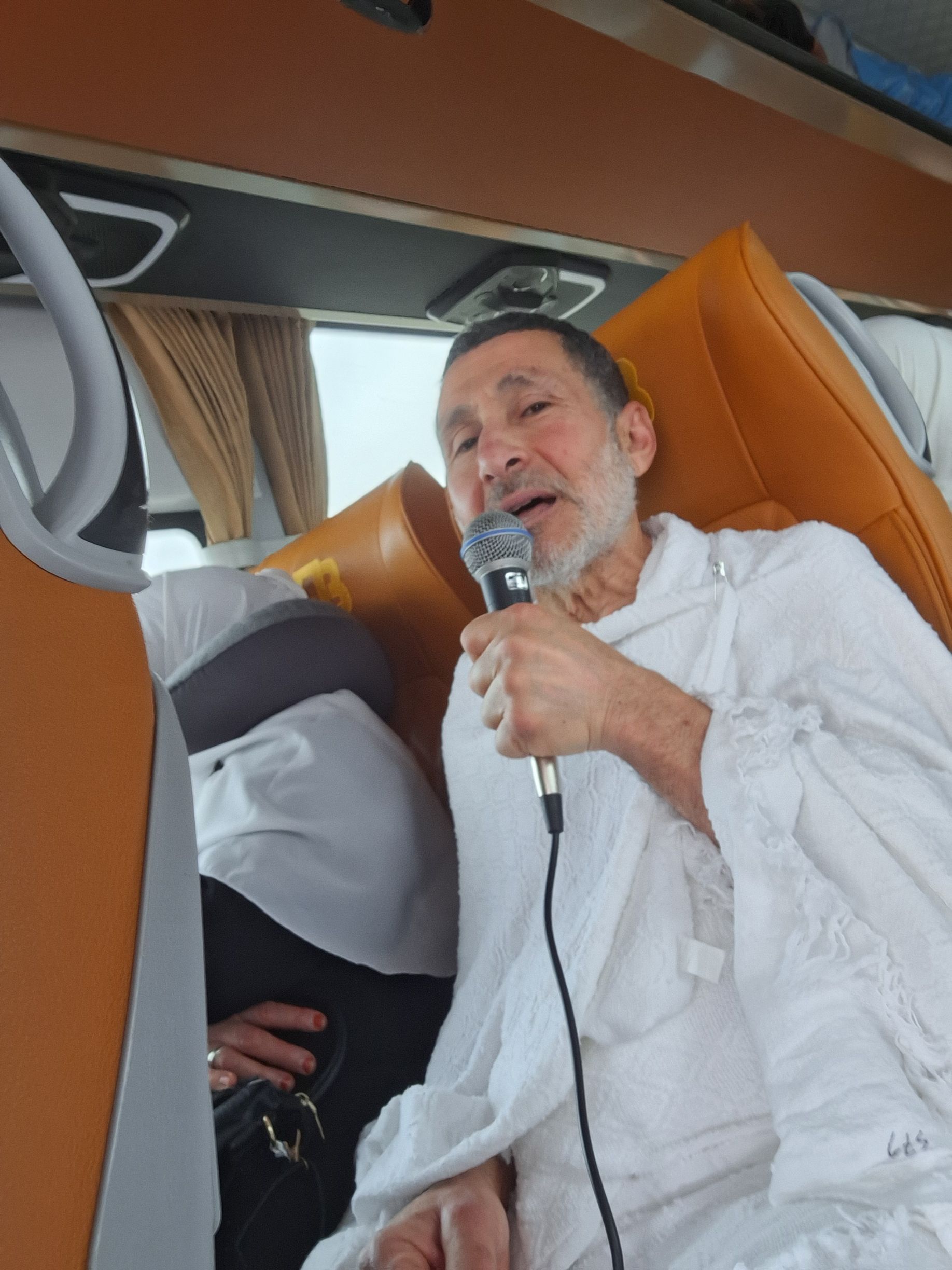 Een man in een wit gewaad zingt in een microfoon