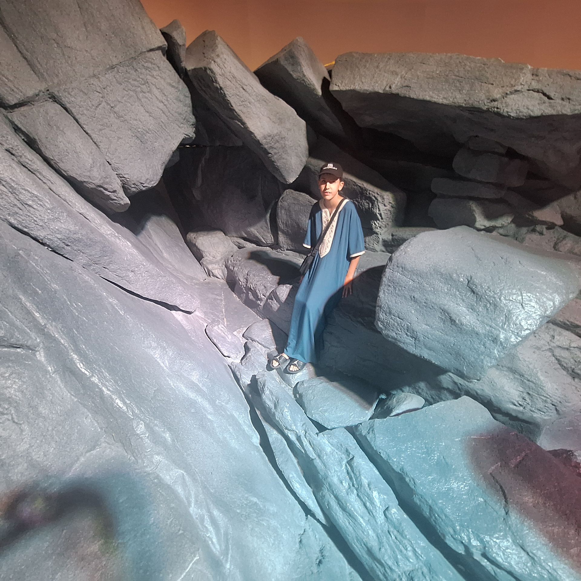 Een man in een blauw shirt staat op een rotsachtige klif