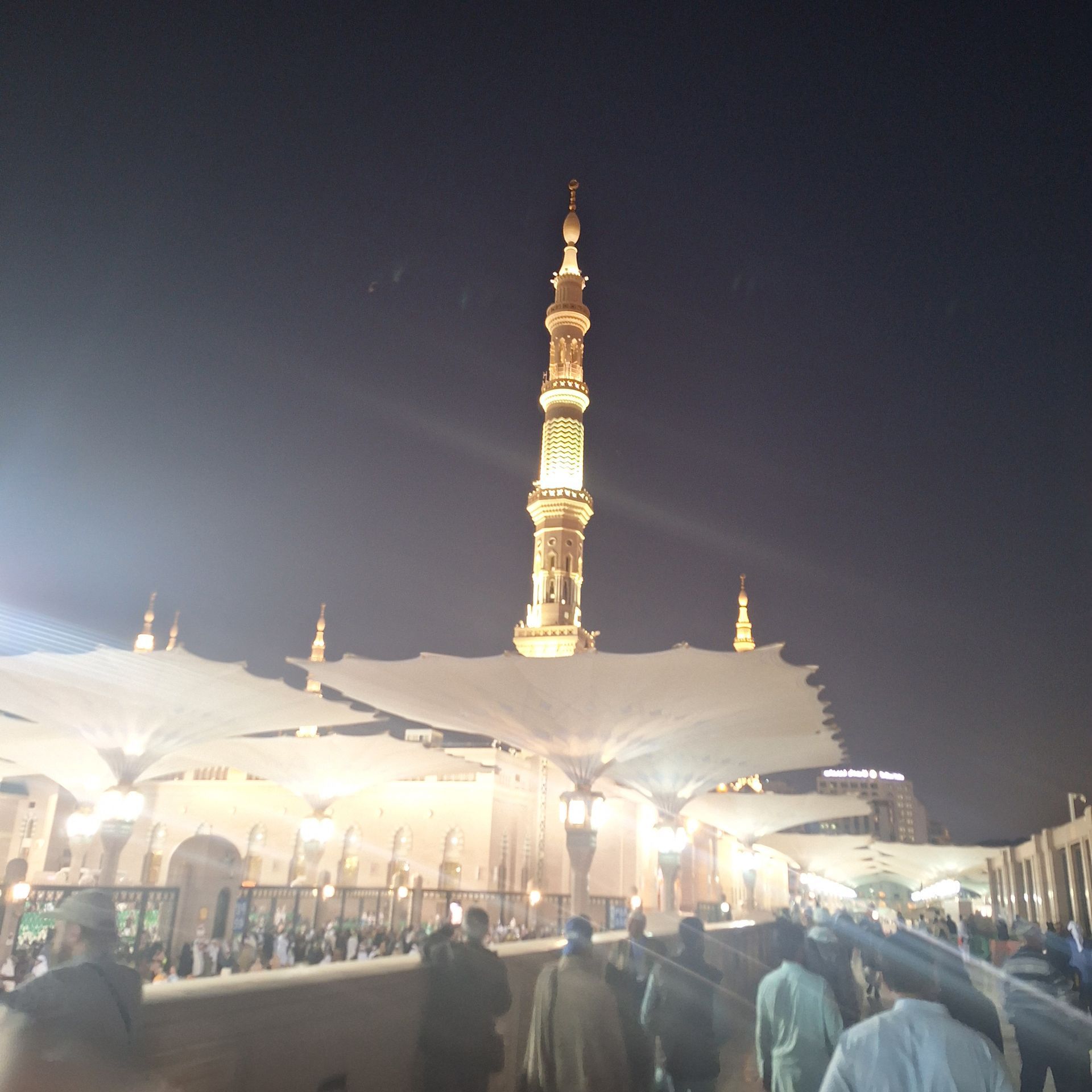 Een groep mensen loopt 's nachts voor een moskee