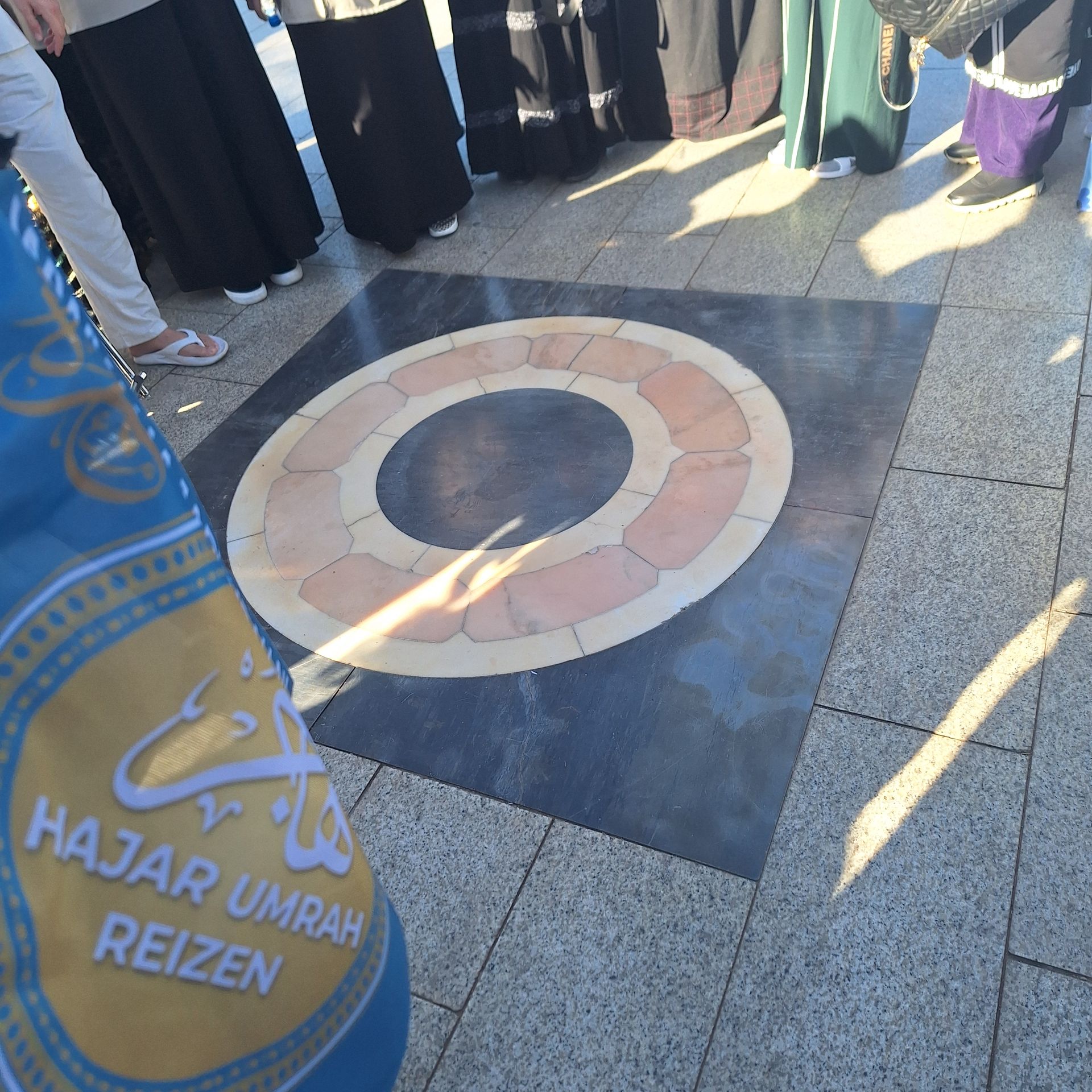 Een groep mensen die rond een cirkel staan ​​met de tekst majar umrah reizen