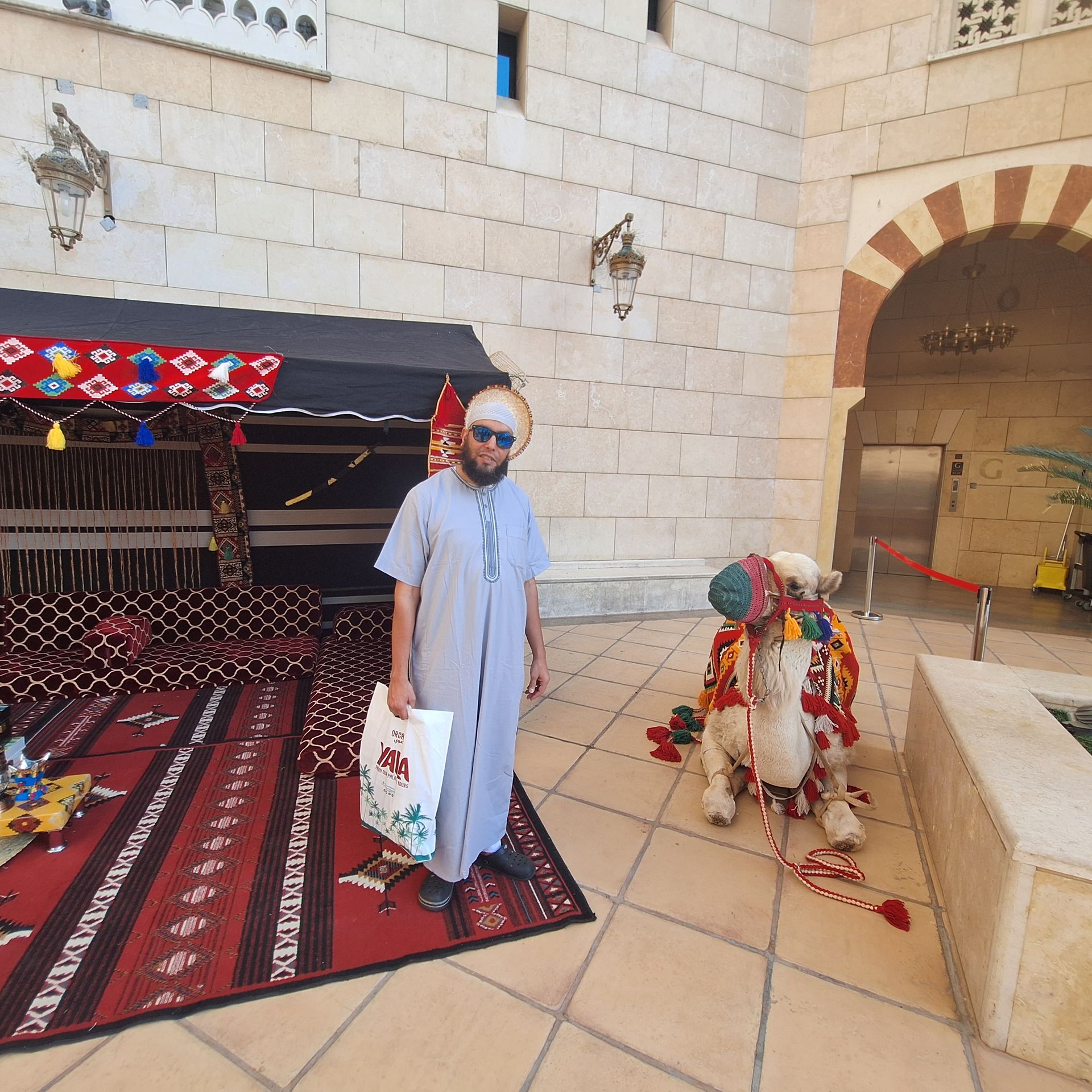 Een man die naast een kameel staat die versierd is met bloemen