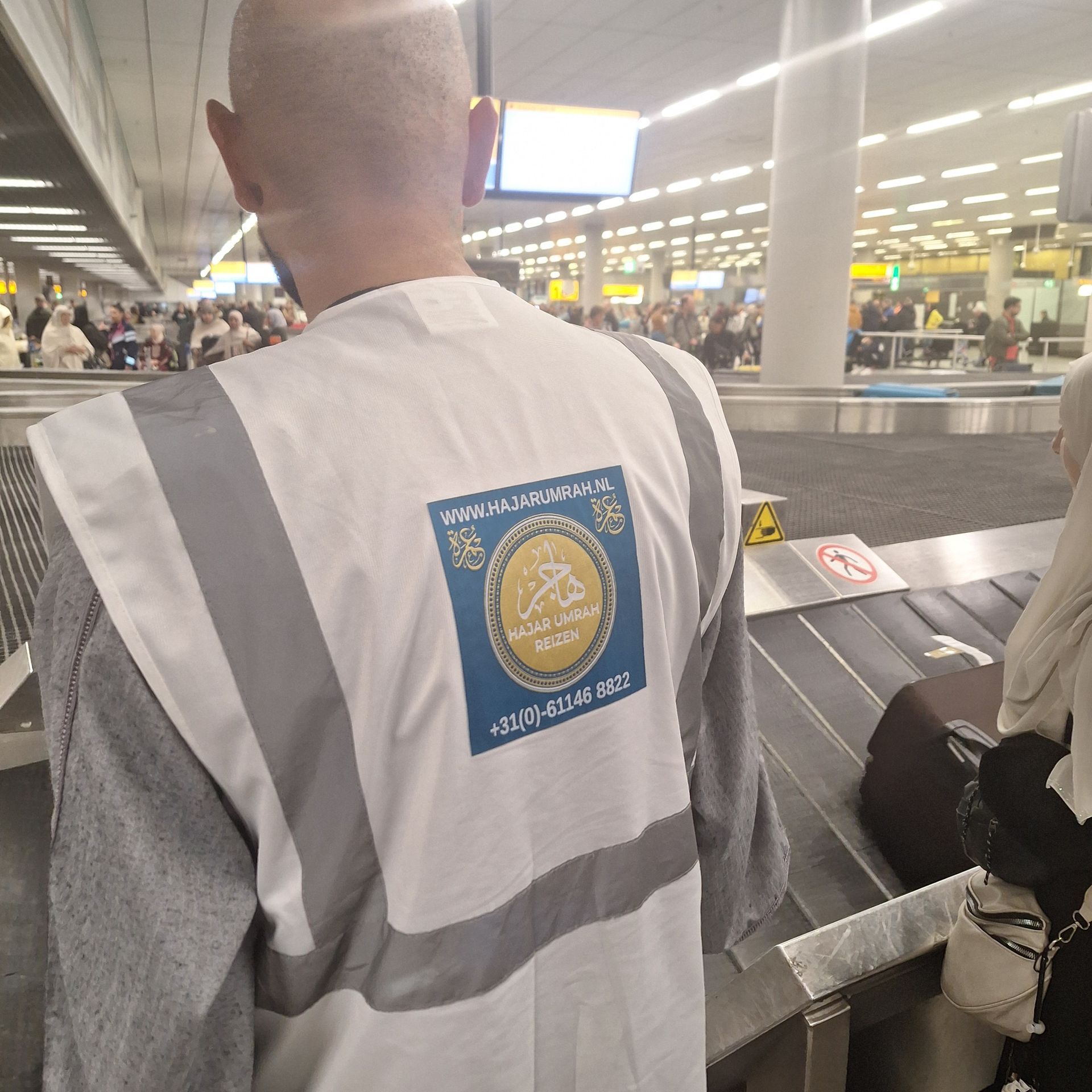 Een man met een veiligheidsvest staat op een luchthaven