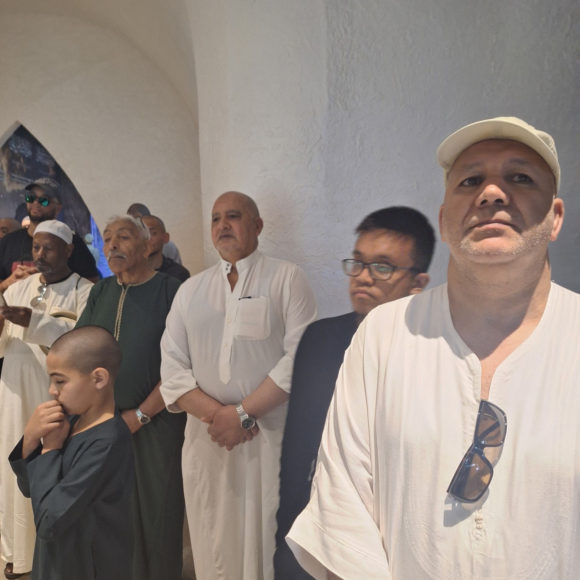 Een groep mannen die in een rij staan, waarvan er één een zonnebril draagt