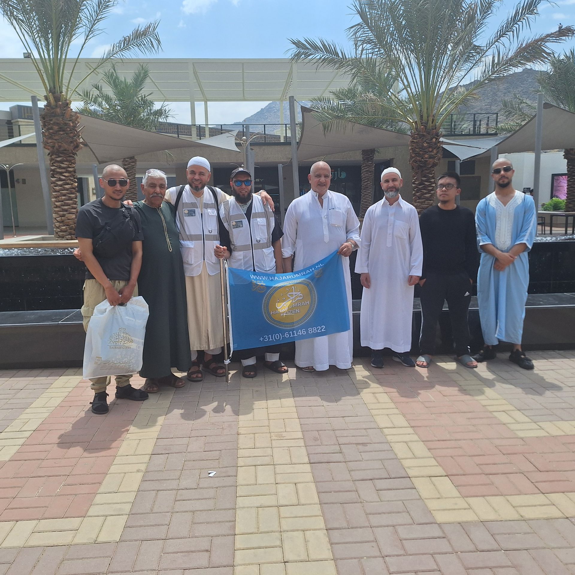 Een groep mannen poseert voor een foto met een blauwe vlag