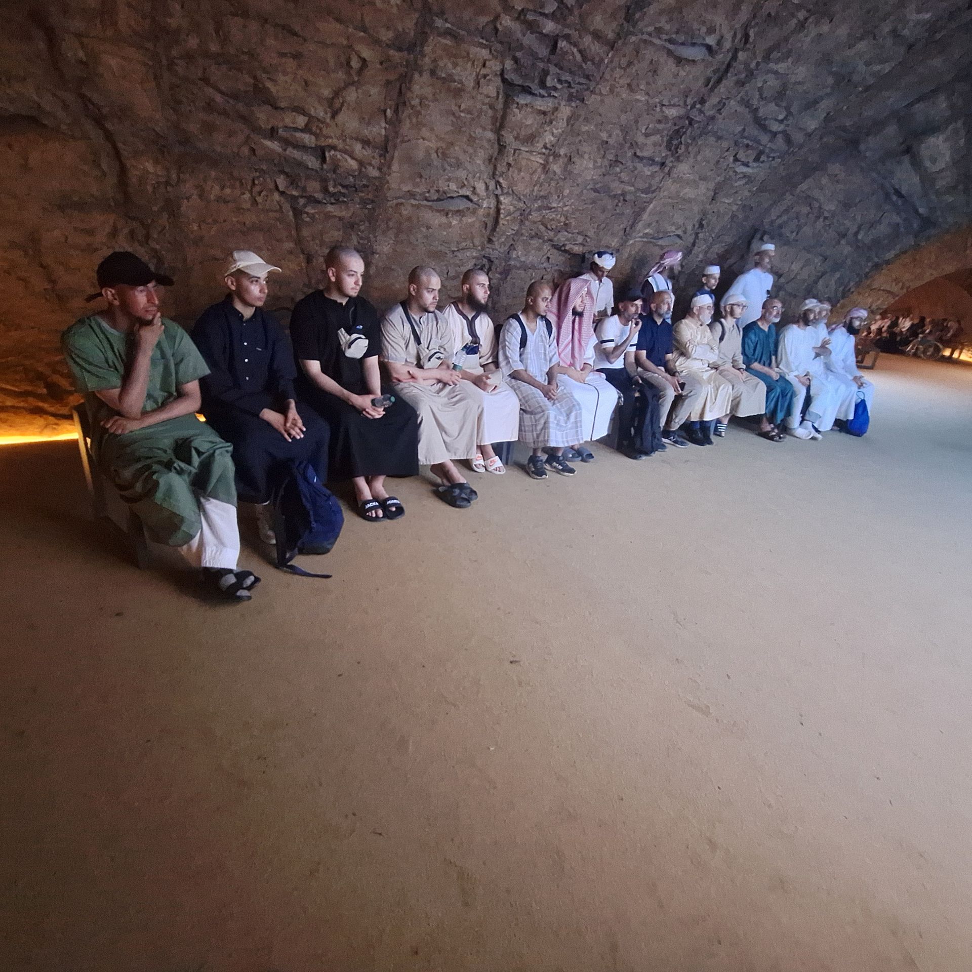 Een groep mensen zit op de grond in een grot