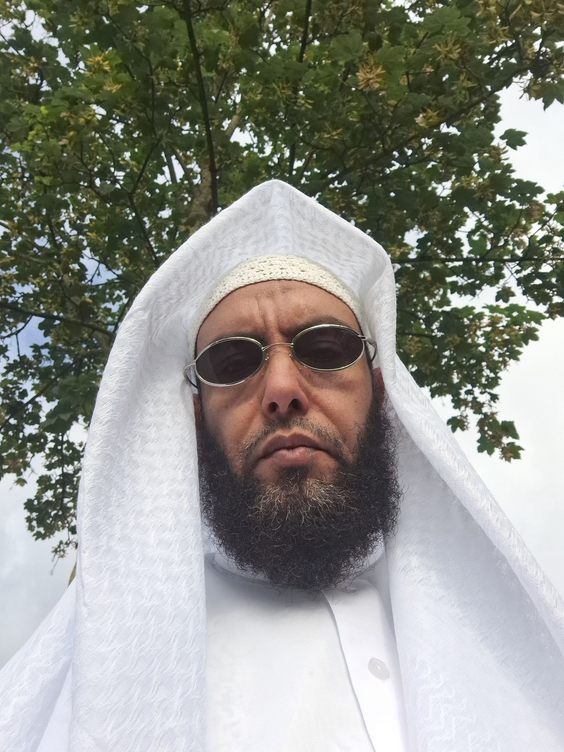 Een man met een baard, een zonnebril en een wit gewaad