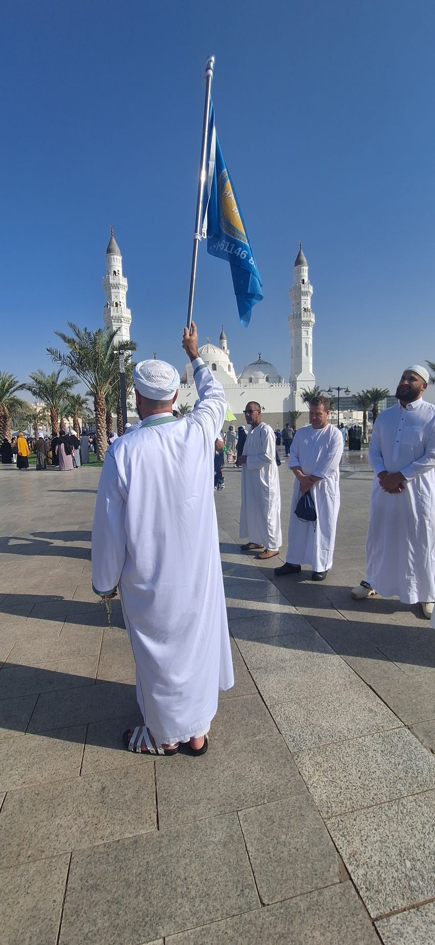 Een man in een wit gewaad houdt een blauw-gele vlag vast.