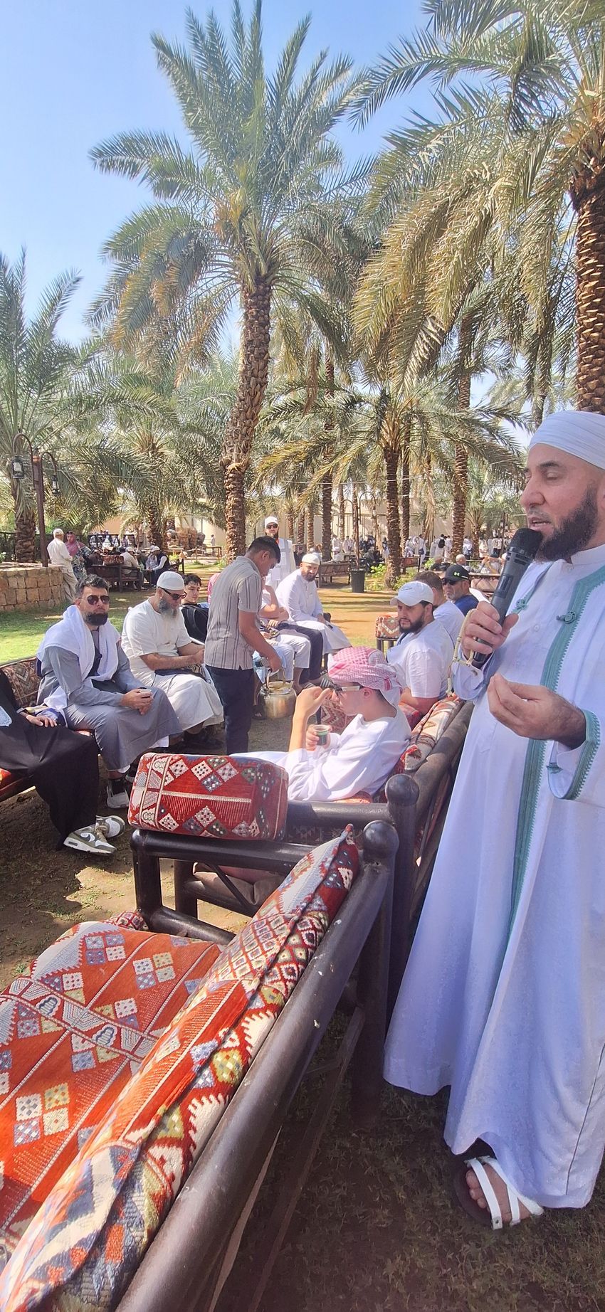 Een man staat voor een groep mensen met een microfoon in zijn handen.
