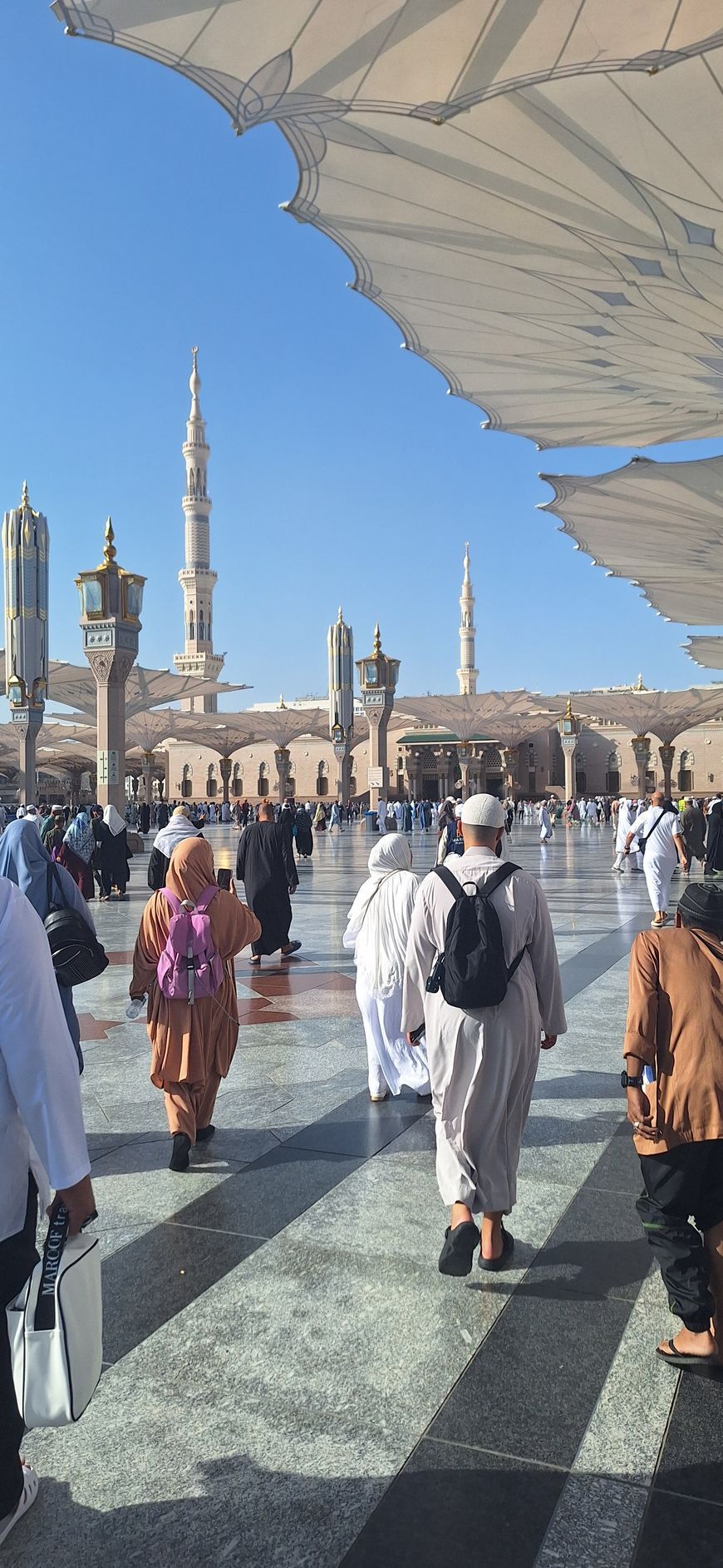 Een groep mensen loopt onder paraplu's voor een moskee.