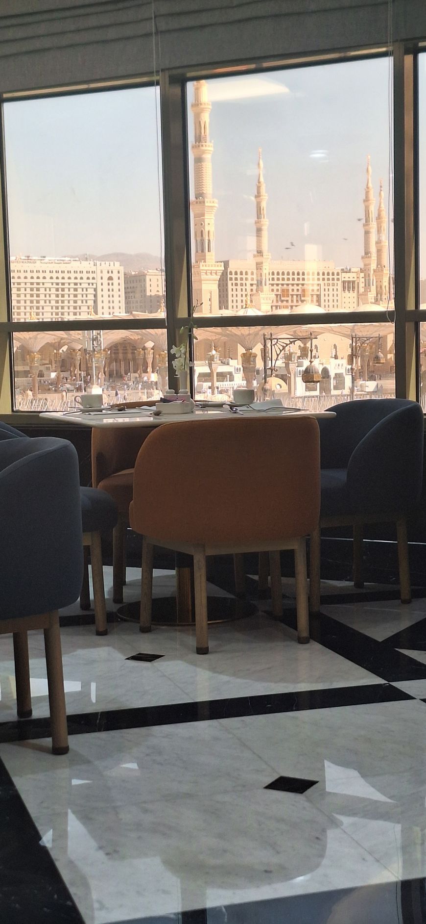 Een eetkamer met tafels en stoelen en uitzicht op een stad.