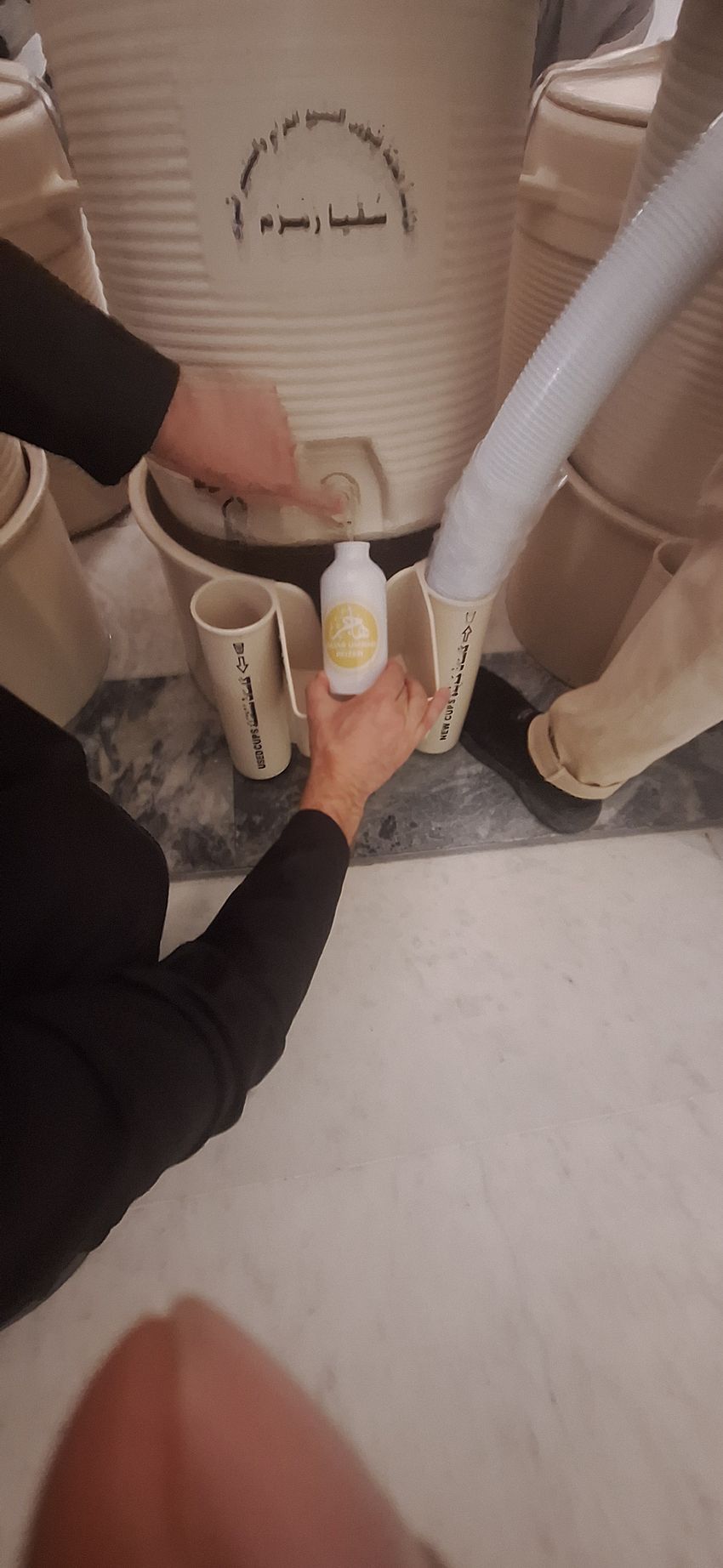 Een persoon houdt een fles met vloeistof voor een toilet.