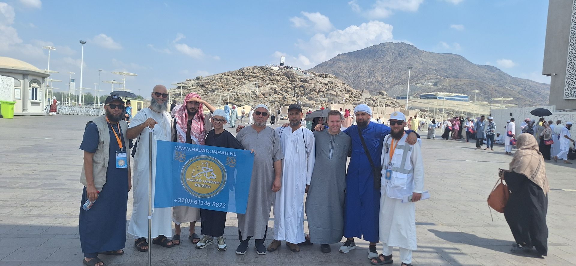 Een groep mensen poseert voor een foto voor een berg.