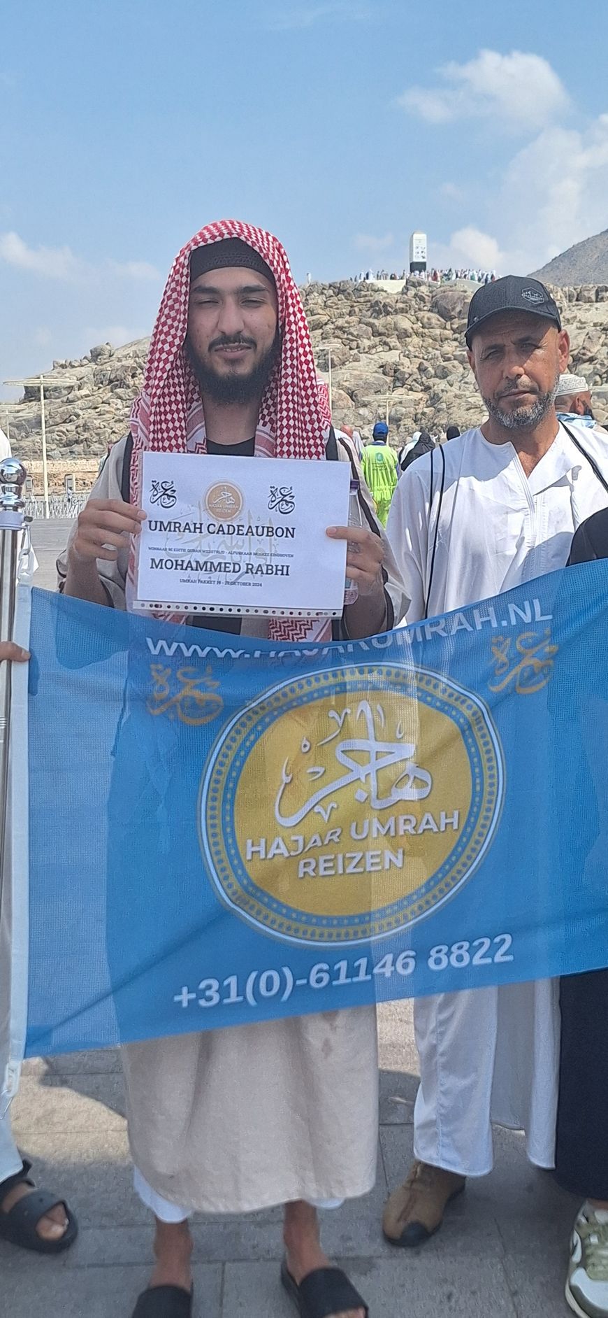 Een man met een tulband houdt een blauwe vlag en een bord vast.