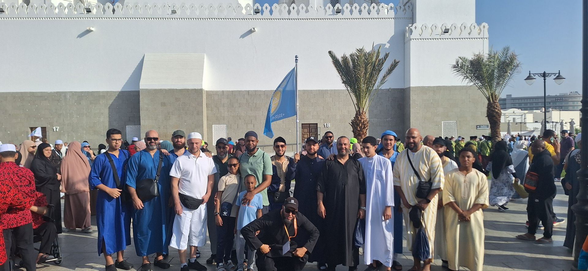 Een groep mensen poseert voor een foto voor een gebouw.