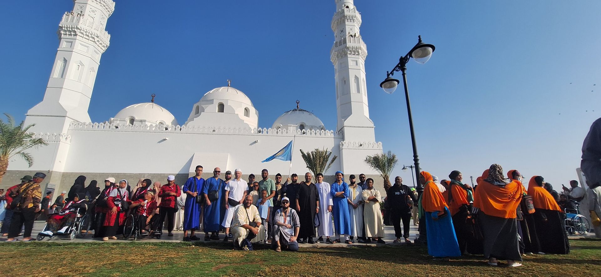 Een groep mensen poseert voor een foto voor een moskee.