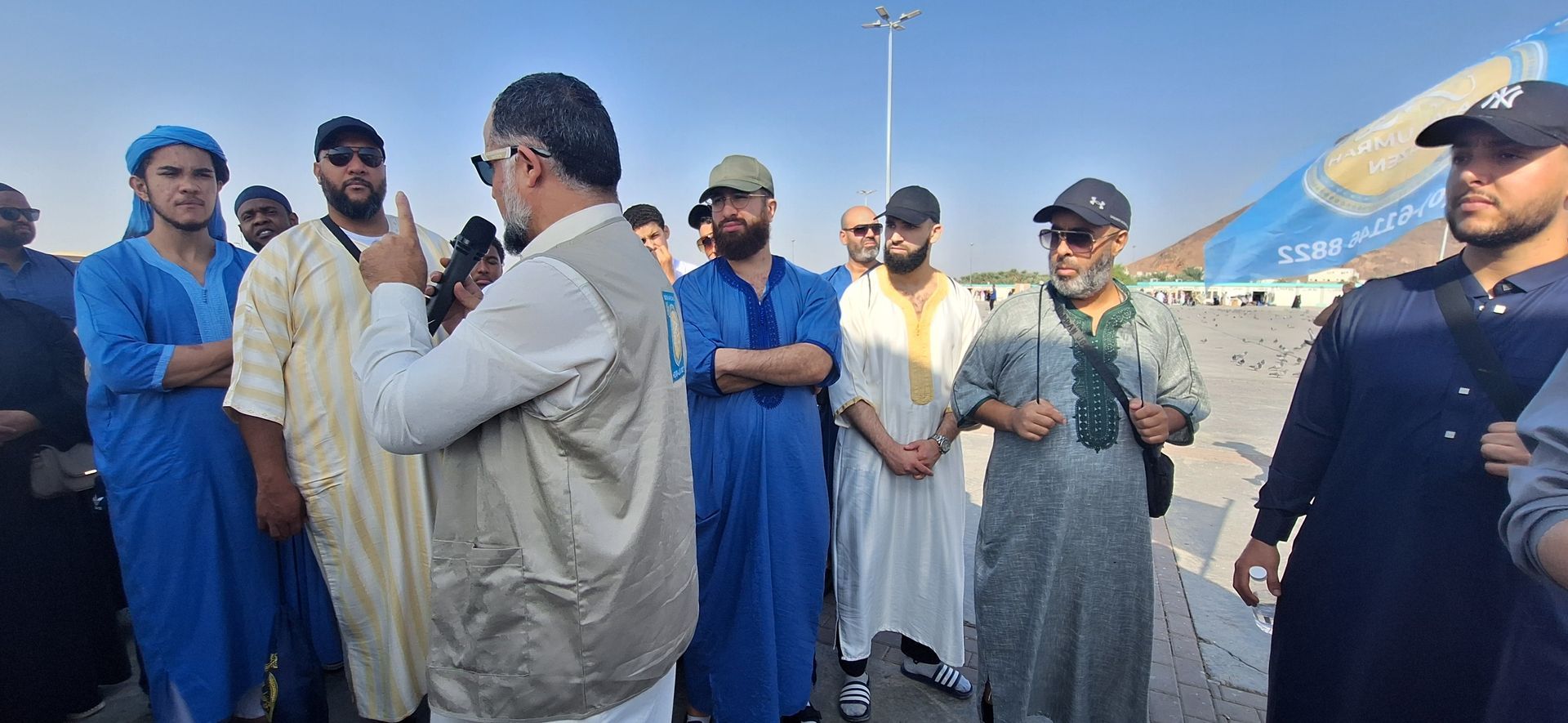 Een groep mannen staat rond een man die aan het bellen is op een mobiele telefoon.