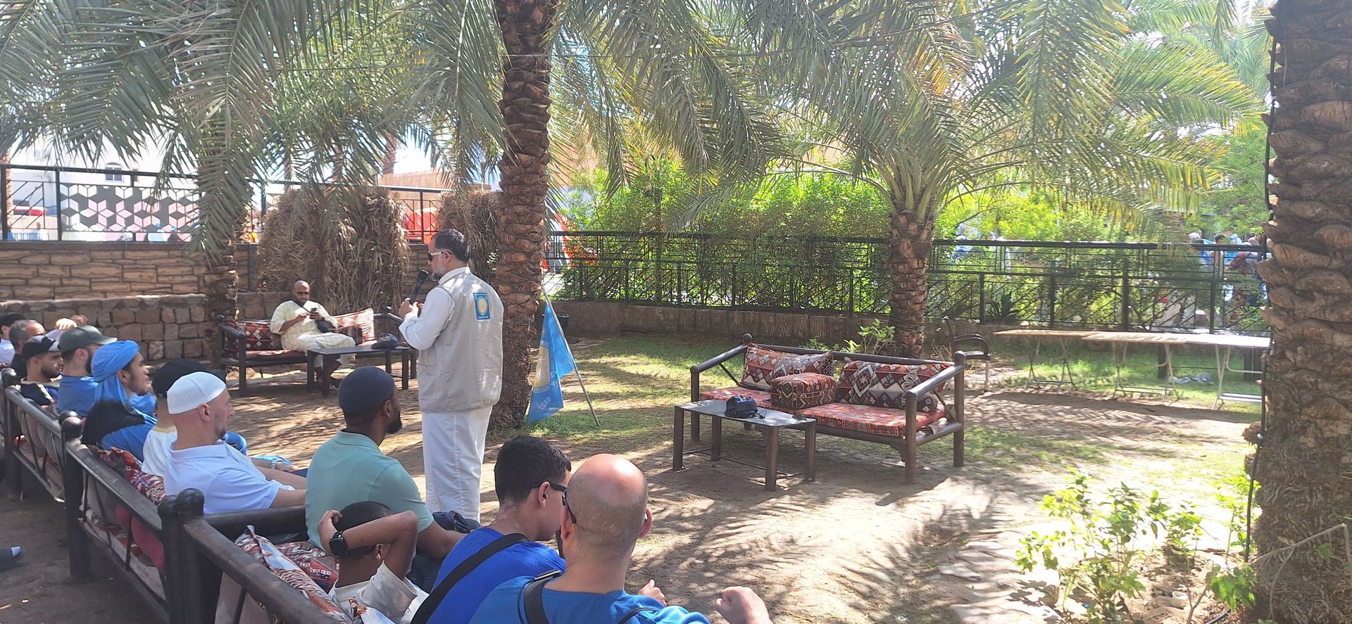 Een groep mensen zit op een bankje in een park.