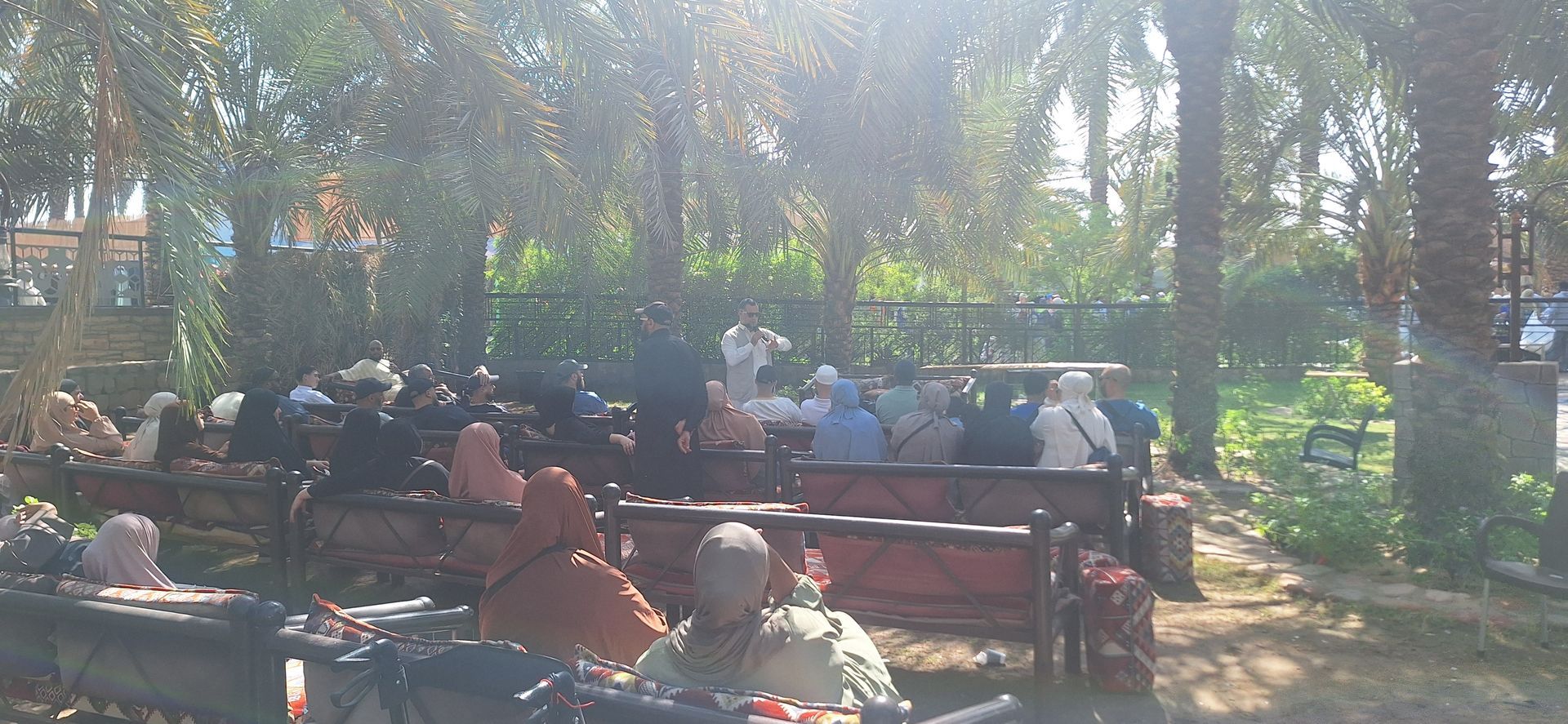 Een groep mensen zit op bankjes in een park.