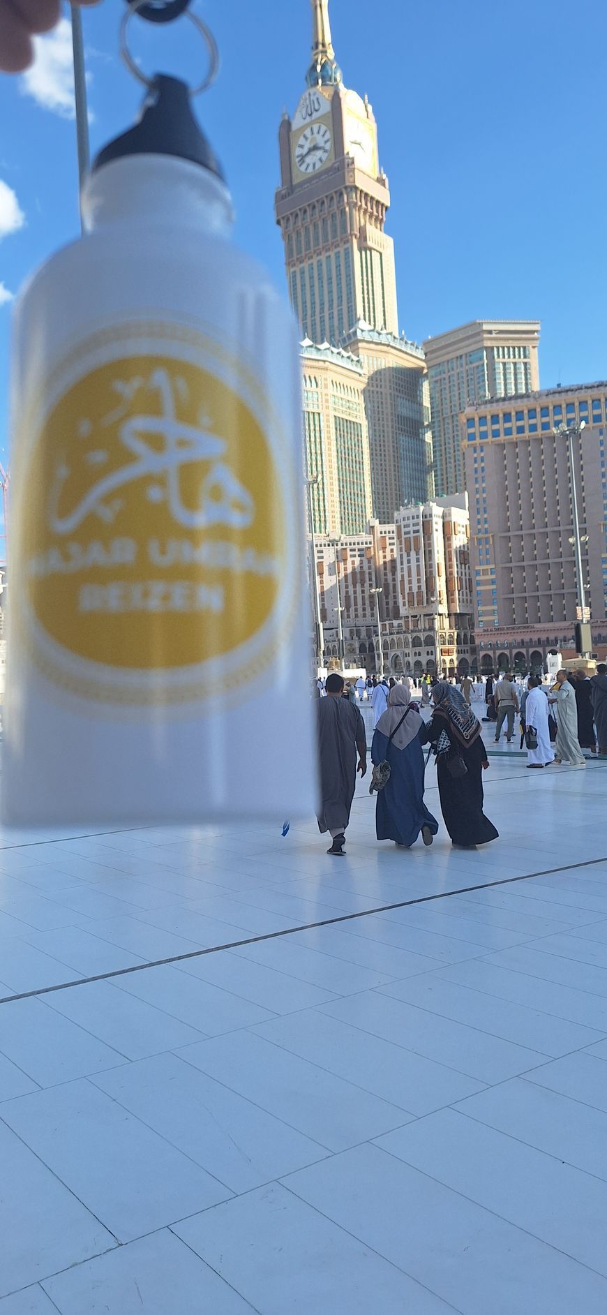 Een persoon houdt een fles water vast voor een klokkentoren.