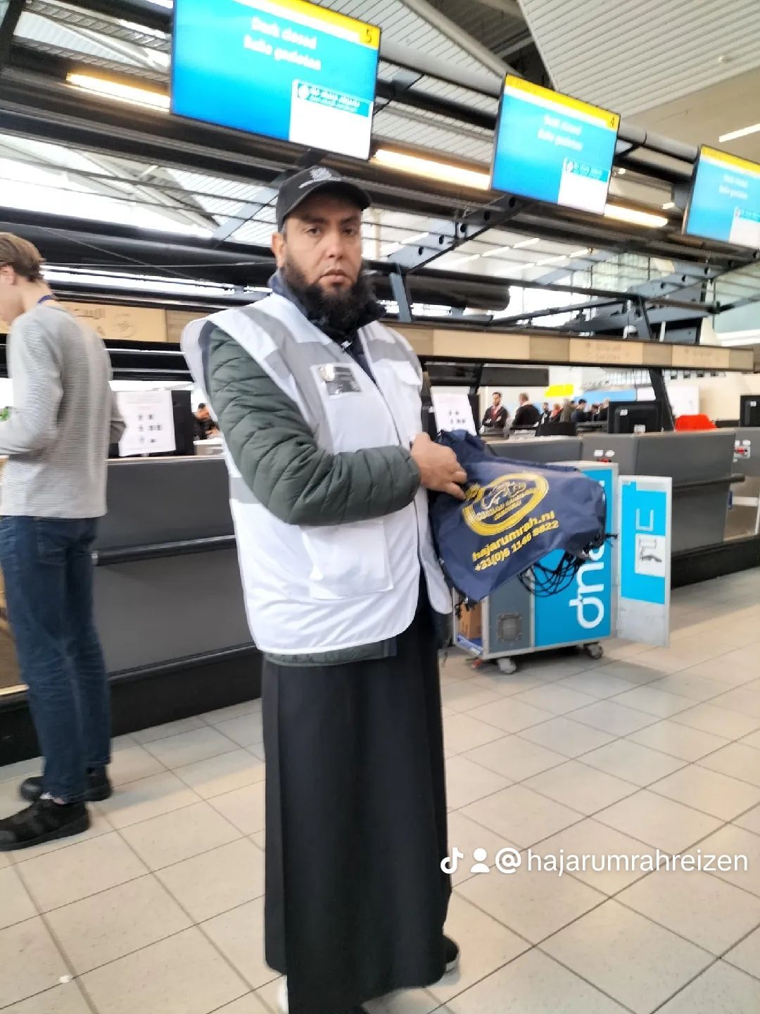 Een man met een baard houdt een tas vast op een luchthaven
