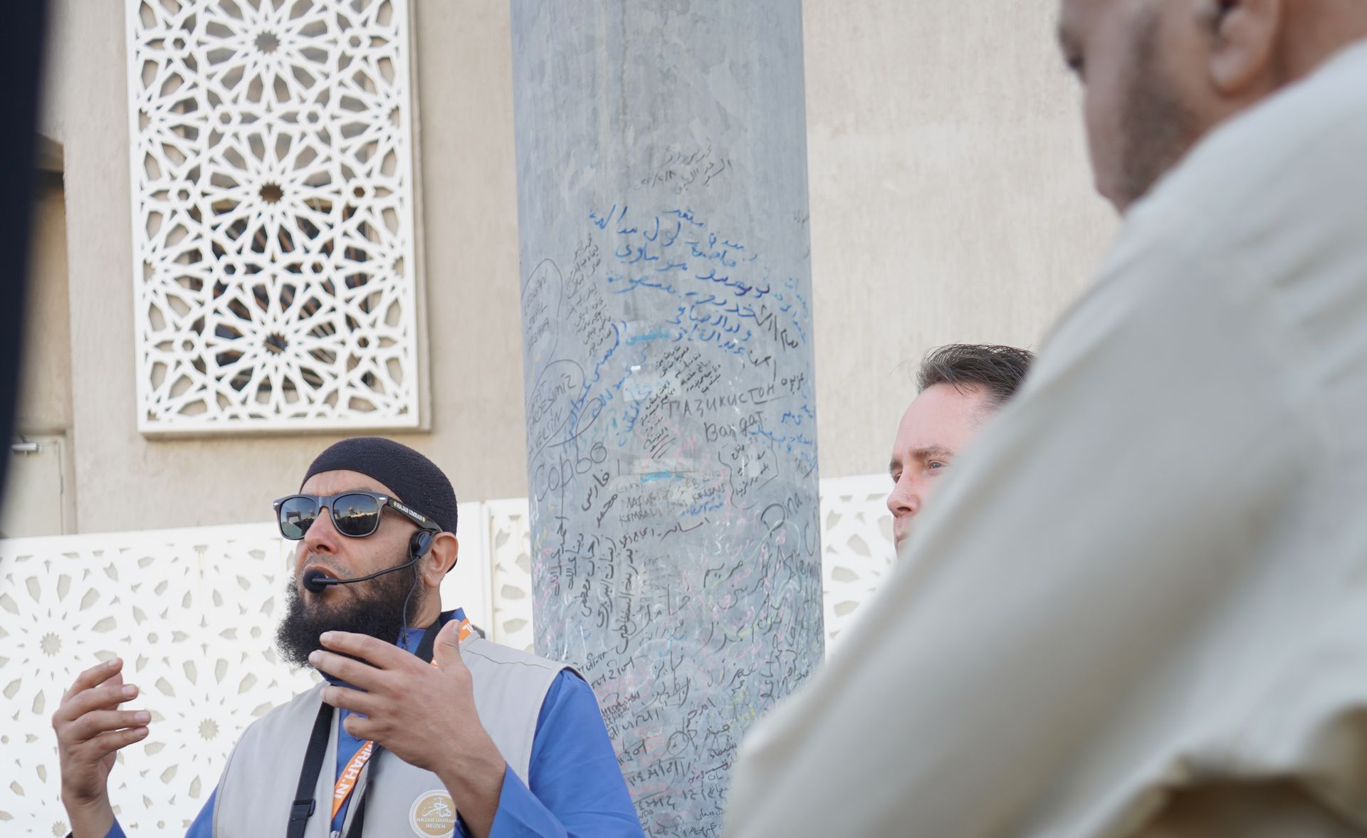 Een man met een baard en een zonnebril praat met een andere man