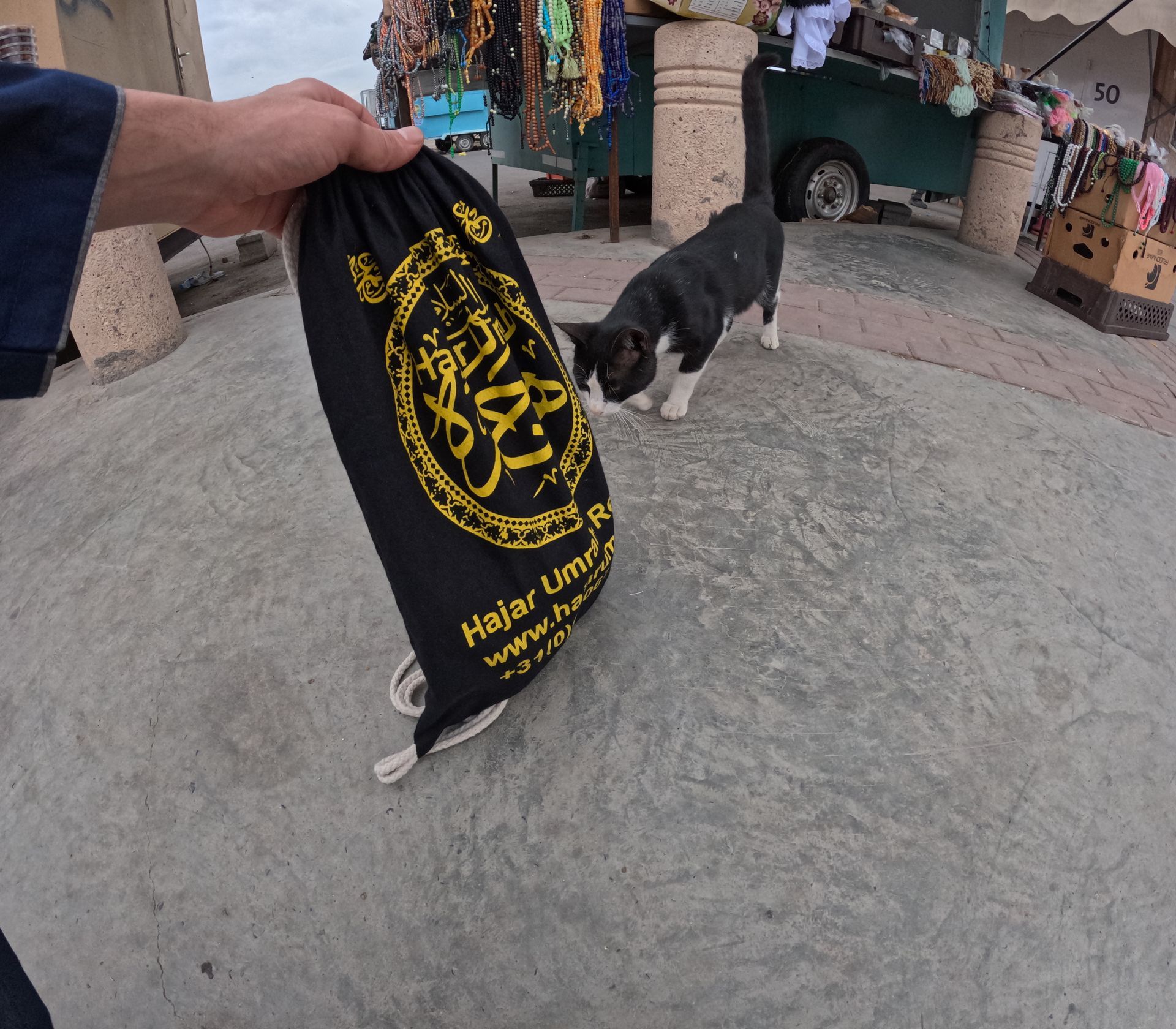 Een persoon houdt een zwarte tas vast met de tekst hajiu love