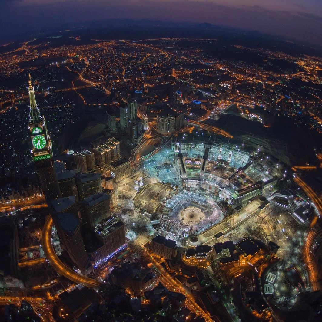 Een luchtfoto van een stad bij nacht met een groene klokkentoren
