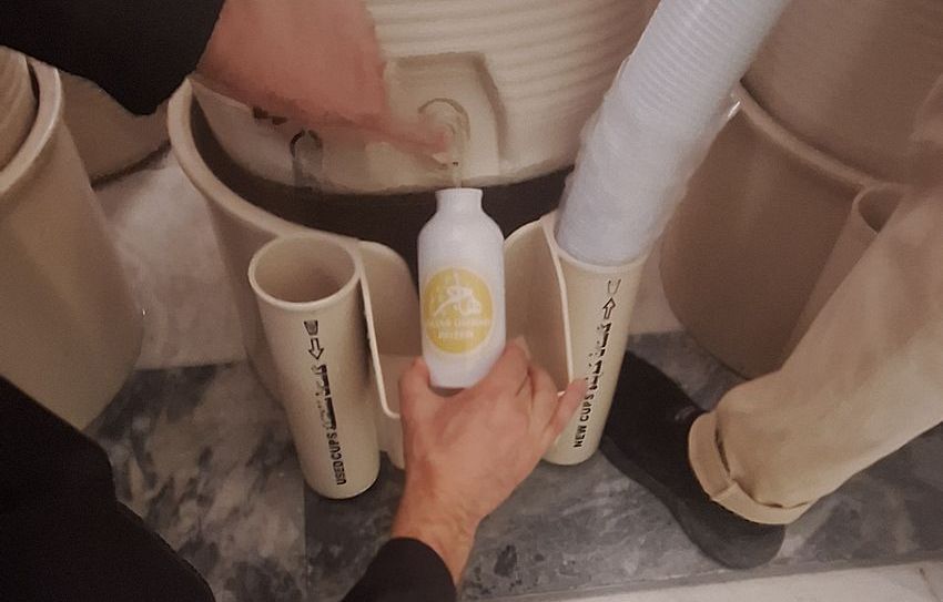 Een persoon houdt een fles vloeistof in zijn hand.