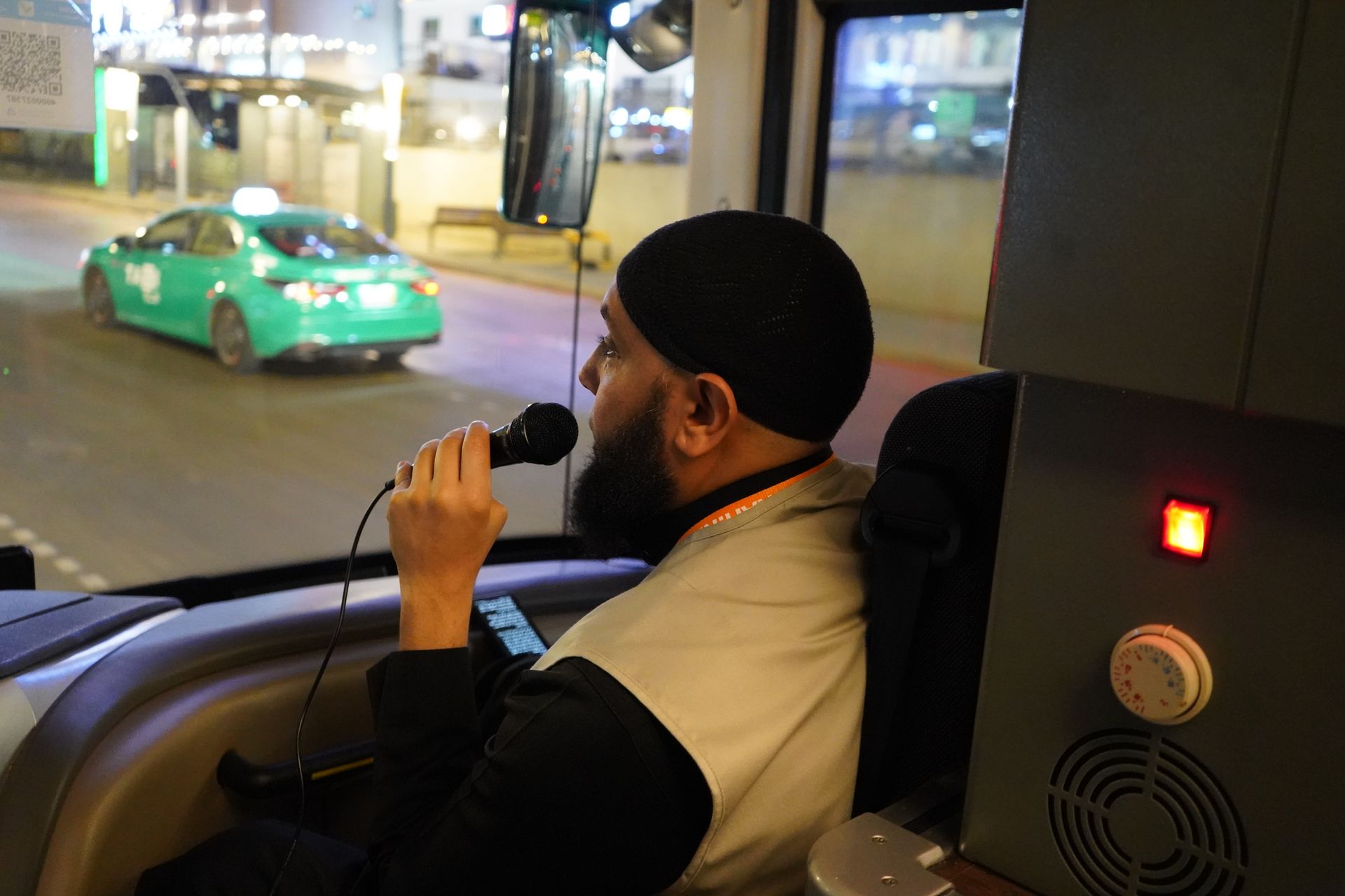 Een man zingt in een microfoon terwijl hij een bus bestuurt.