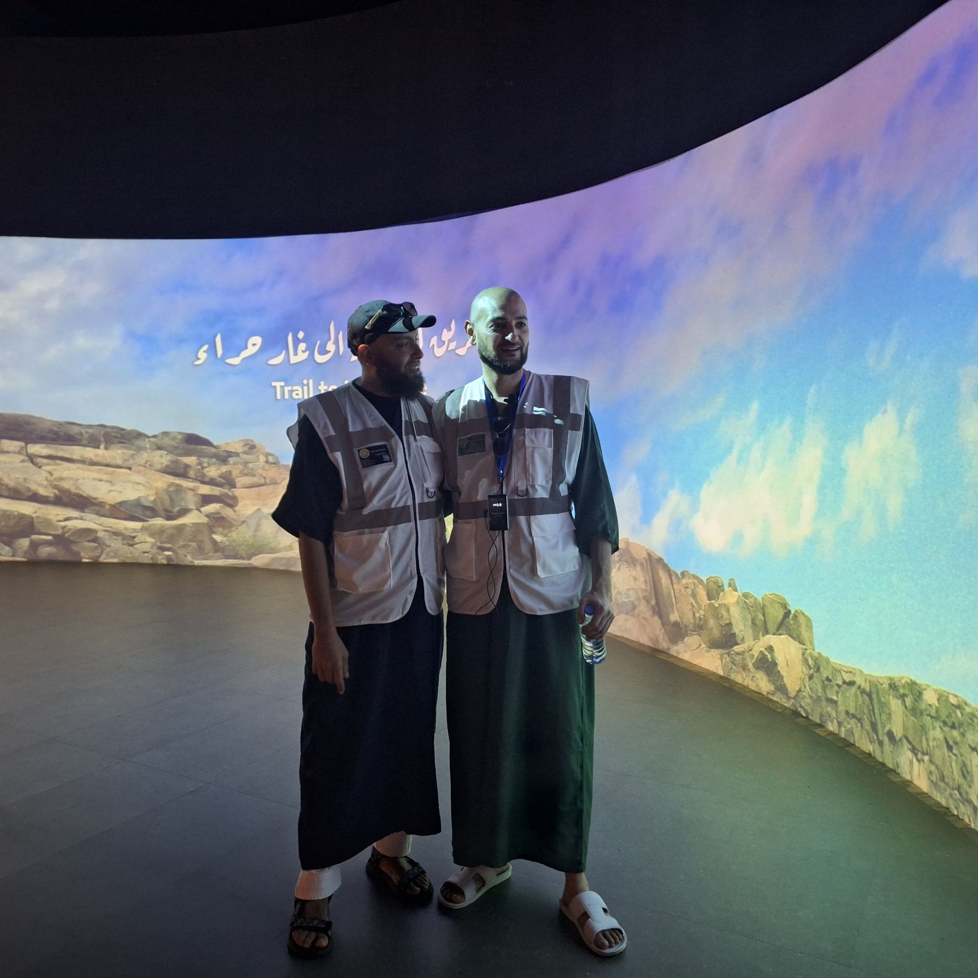 Twee mannen staan ​​voor een groot scherm met Arabische letters erop